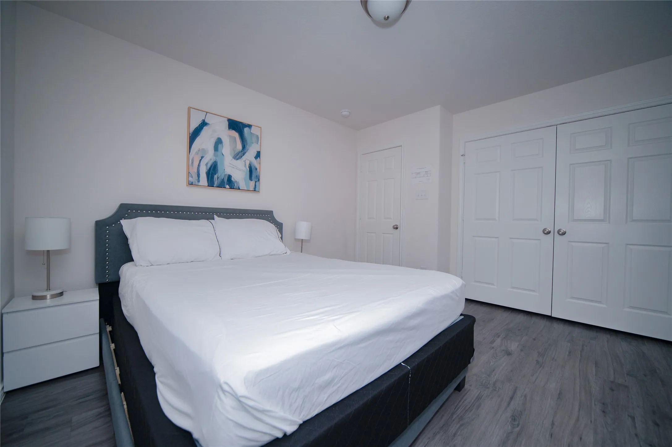 Wood-finish flooring, white walls, and a white paneled door