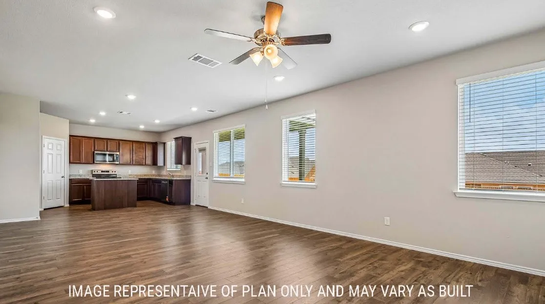 Wood-finish flooring, recessed lighting, ceiling fan, multiple windows, and a kitchen with wood cabinetry