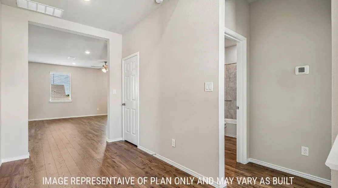 Wood-finish flooring throughout, light-toned wall paint, recessed lighting, and a paneled interior door