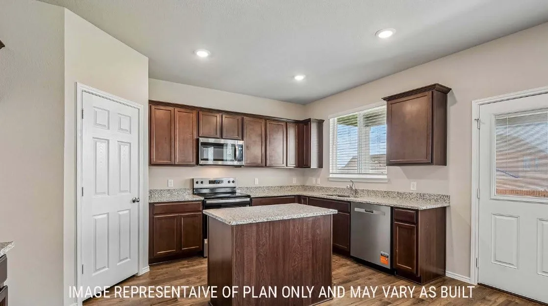 Kitchen featuring wood-finish cabinetry, light-toned countertops, and a central island