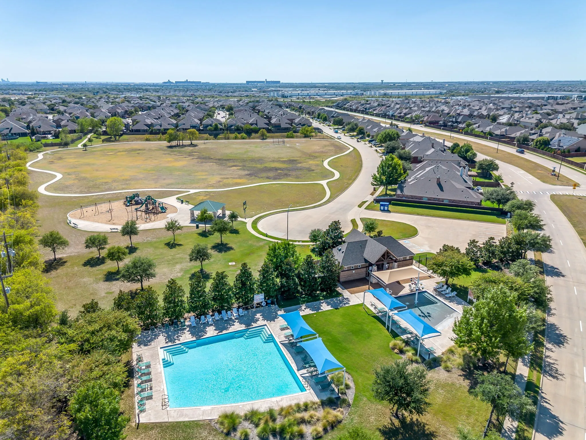 Community features include a swimming pool, covered outdoor seating areas, a playground, a recreational field, and paved walking paths