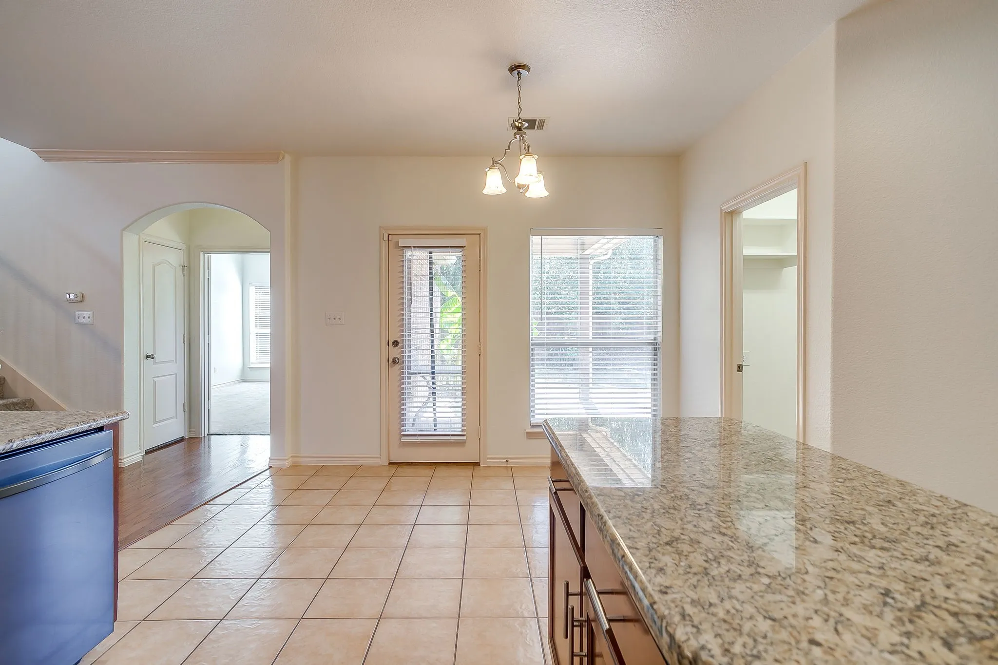 Tile flooring, granite-style countertop island, pendant lighting fixture, glass-paned door, and built-in shelving