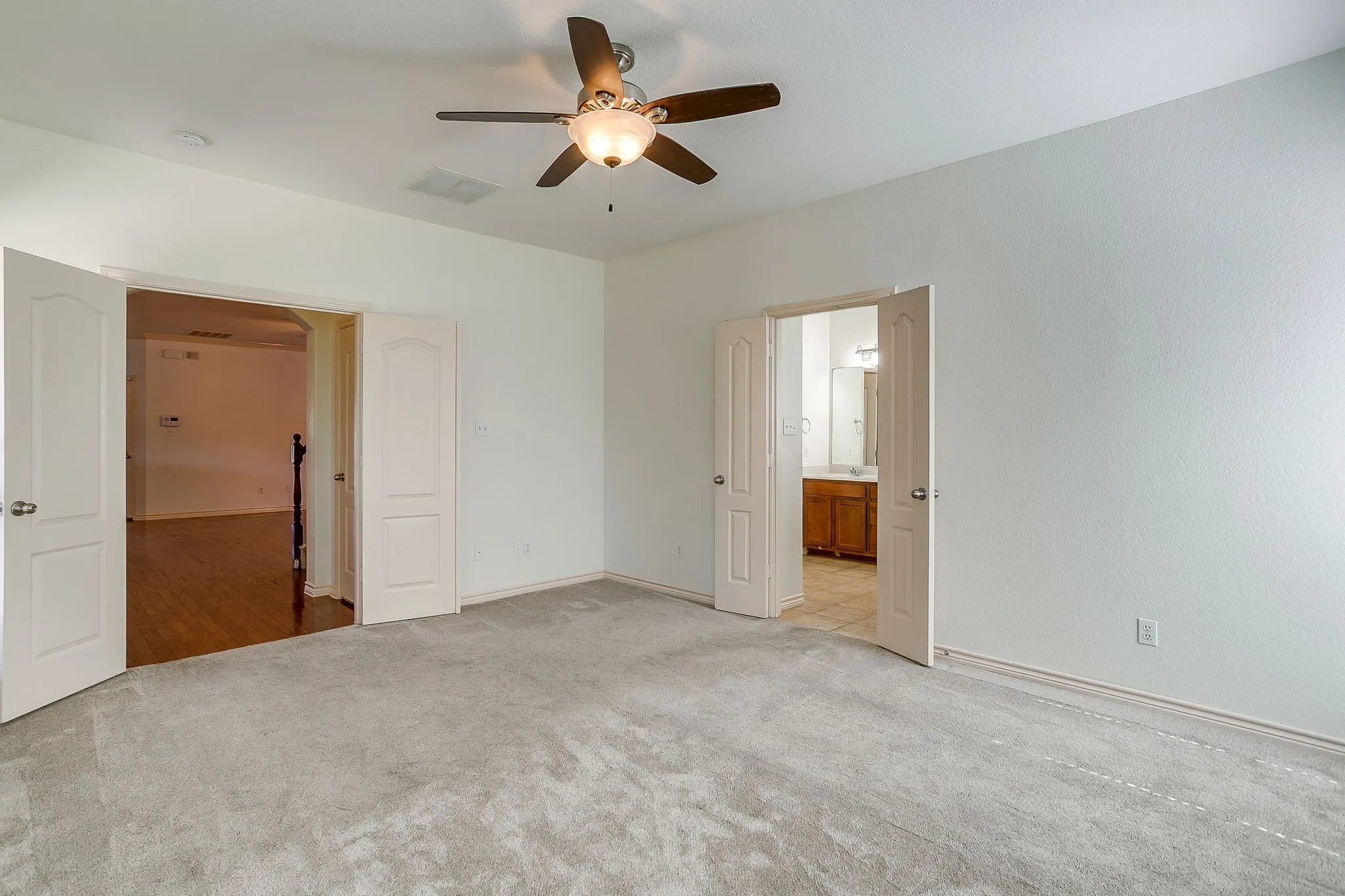 Spacious room with light-colored carpeting and a ceiling fan