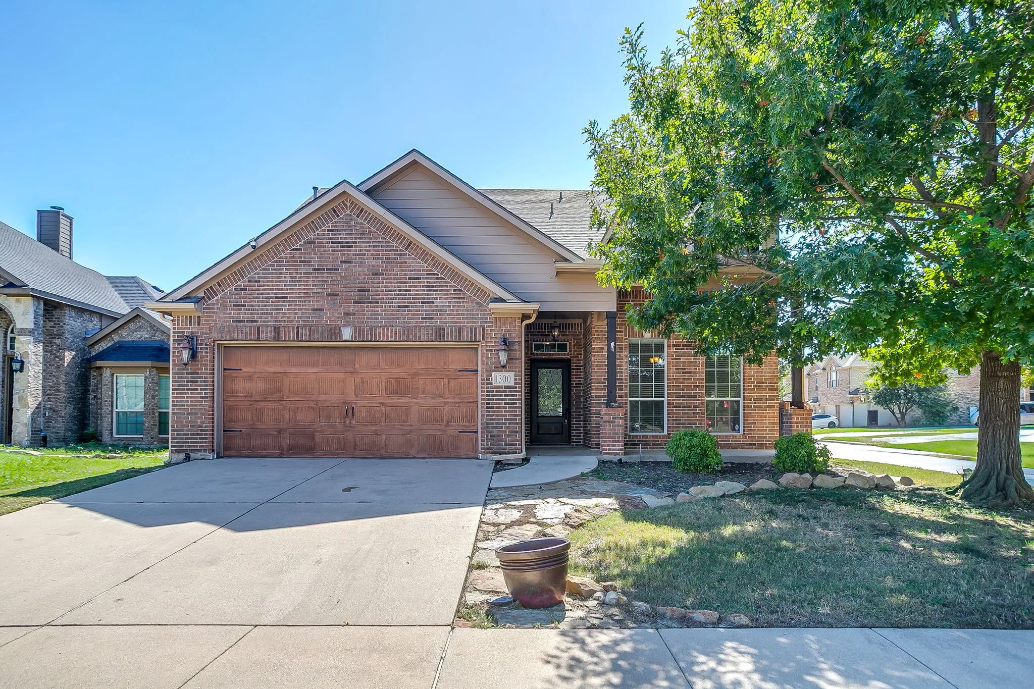 Brick-front exterior with a gabled roofline, concrete driveway, and covered entry