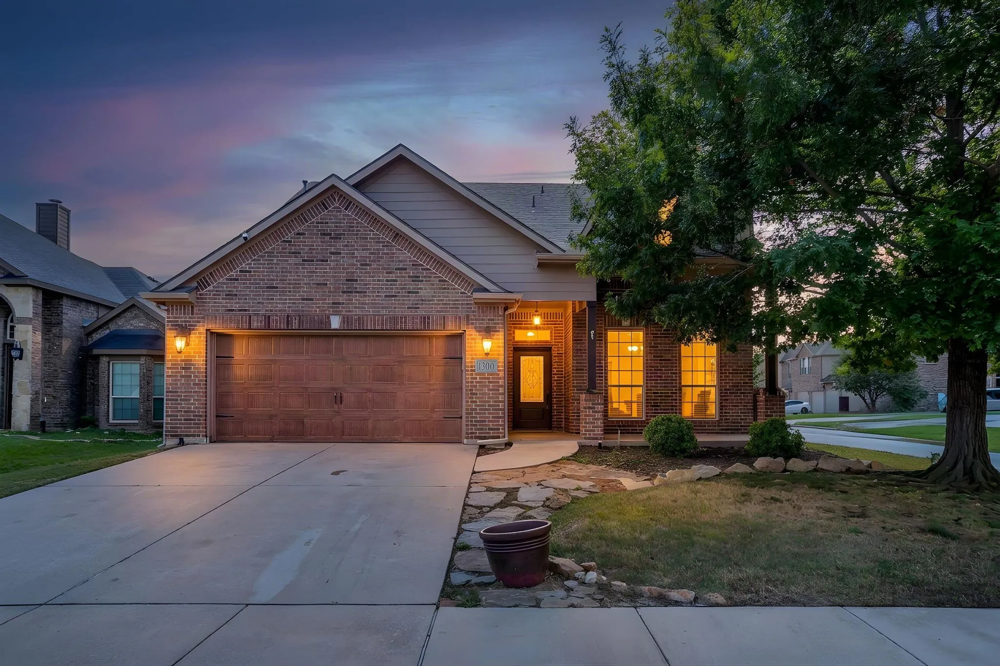 Brick exterior with stone accents, covered front entry, two-car garage, and concrete driveway