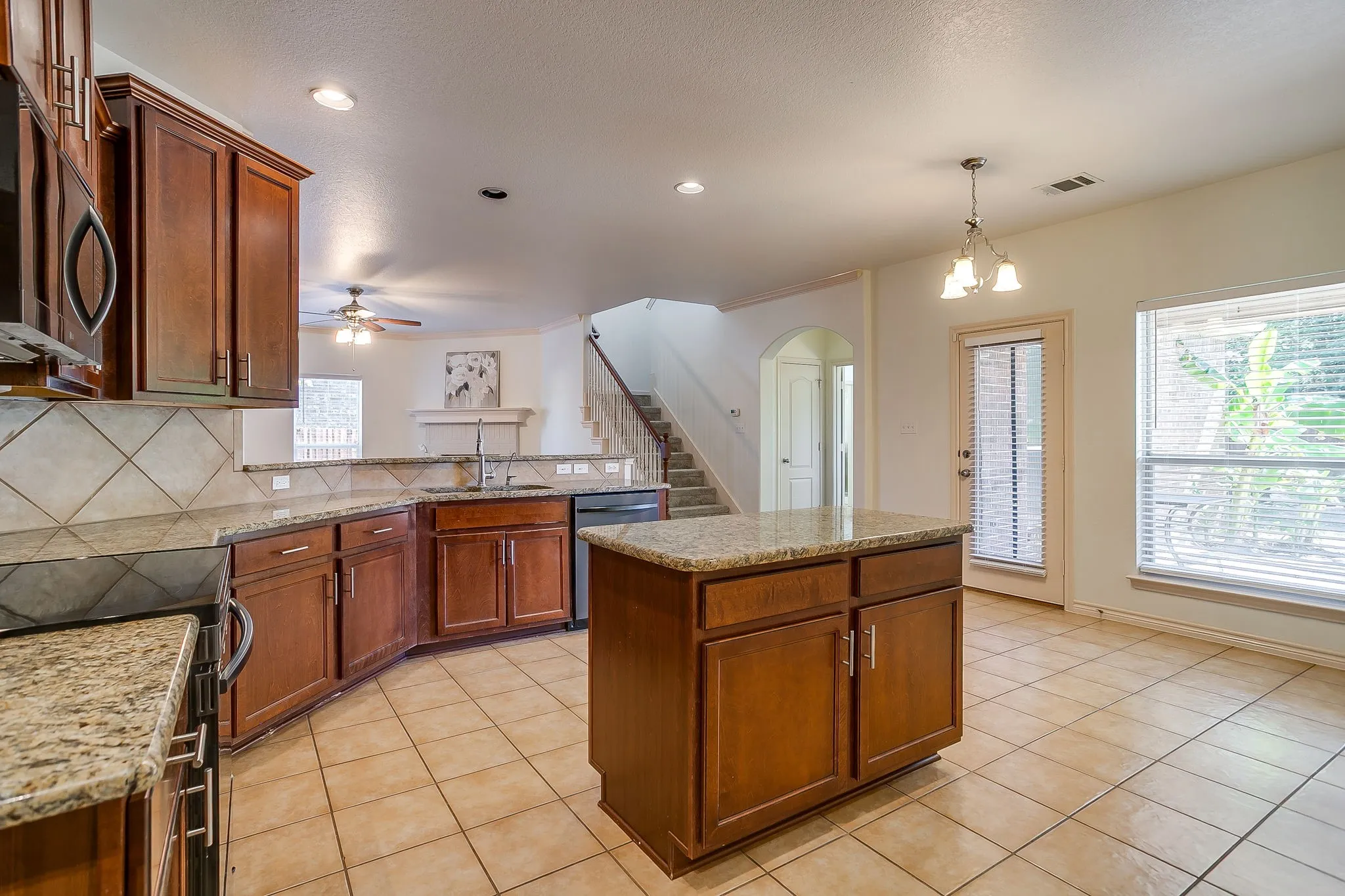 Kitchen featuring granite countertops, wood cabinetry, tile flooring, and a central island