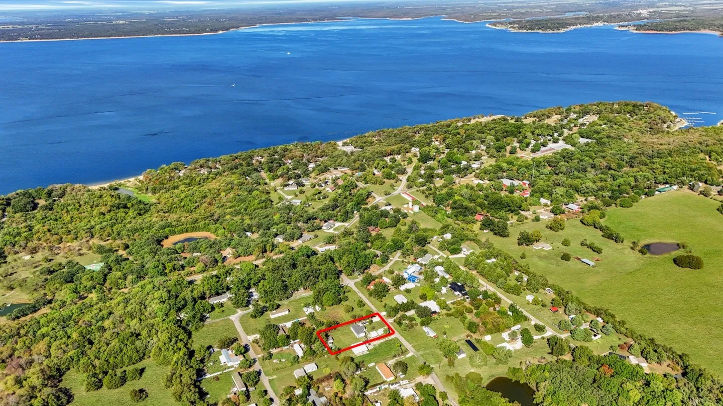 Expansive property with a defined boundary, surrounded by mature trees, and positioned near a large body of water