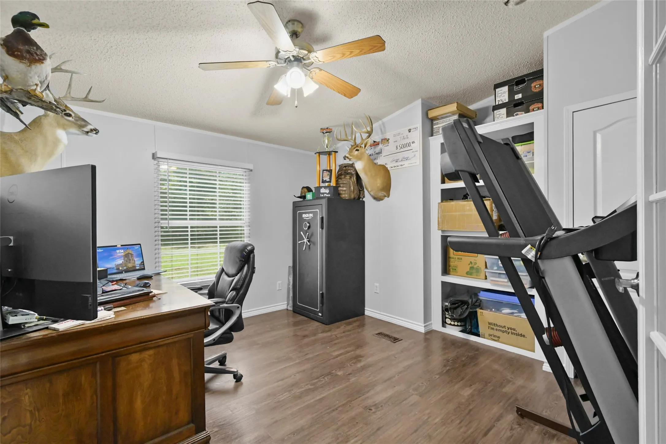 Wood-finish flooring, ceiling fan, built-in shelving, white trim, and a window with blinds