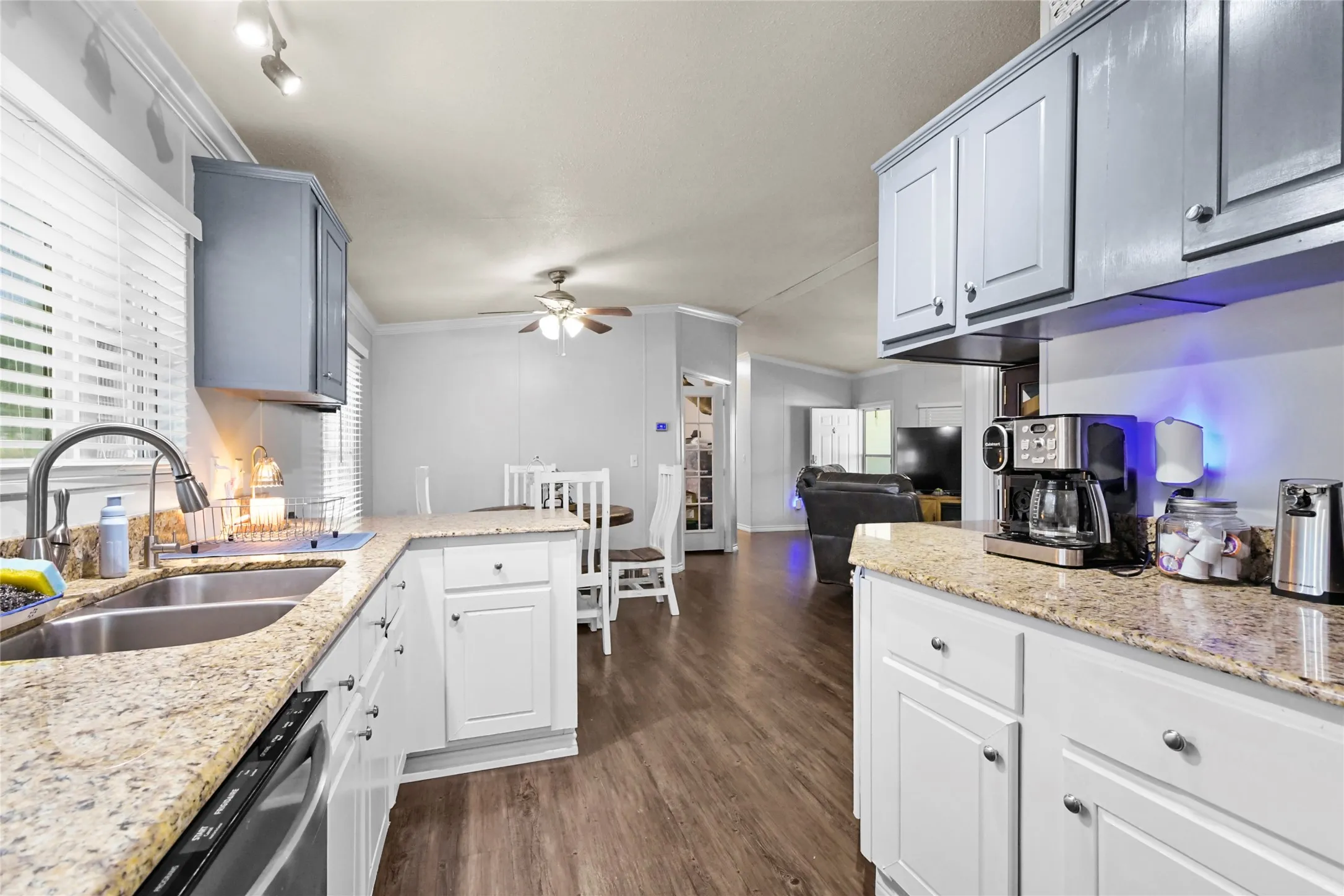 Kitchen with wood-finish flooring, granite countertops, white cabinetry, and a dual-basin stainless steel sink with a gooseneck faucet