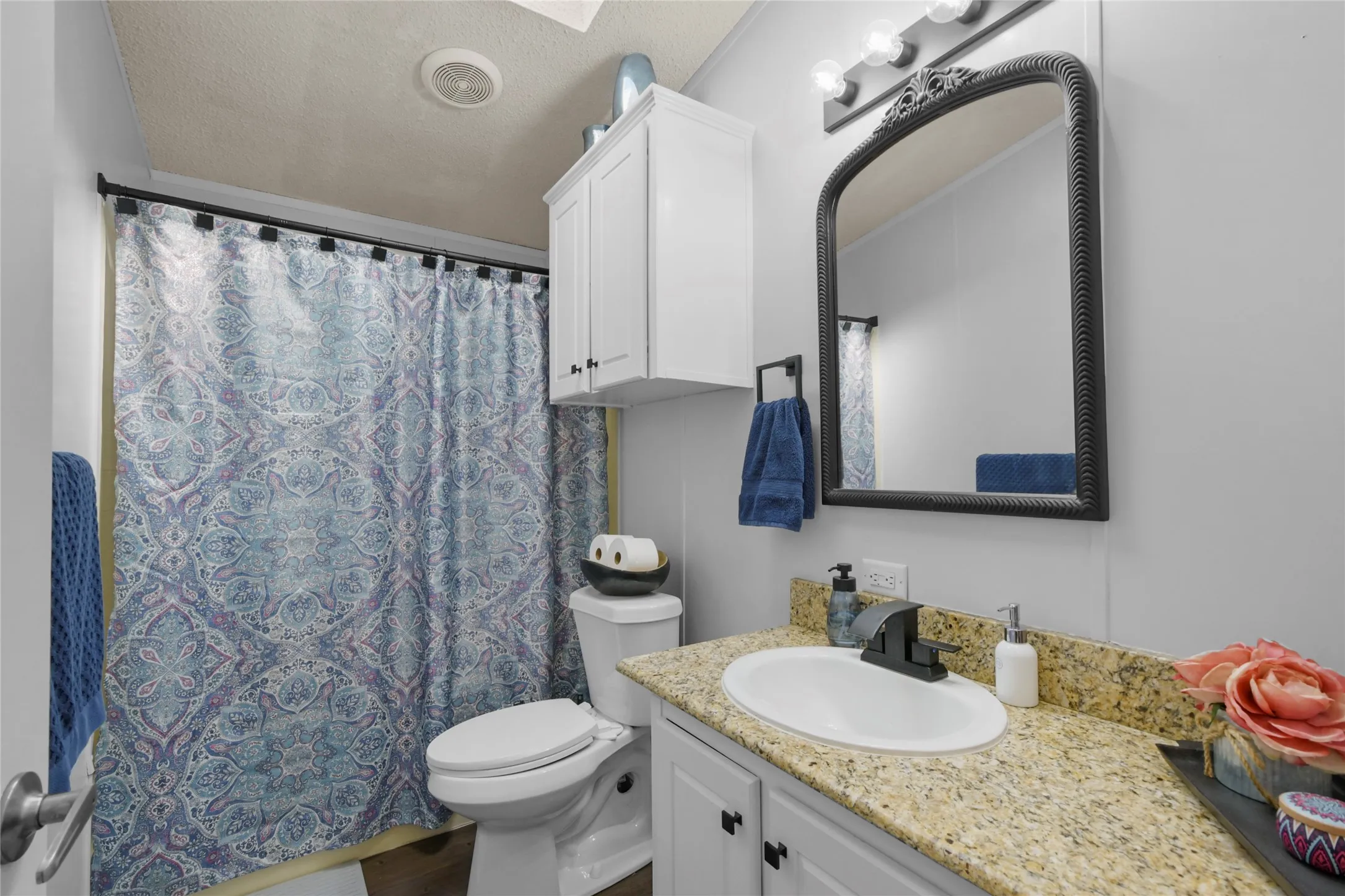 Spa-inspired bathroom featuring a granite-topped vanity with an undermount circular sink, brushed nickel faucet, and ample storage cabinetry