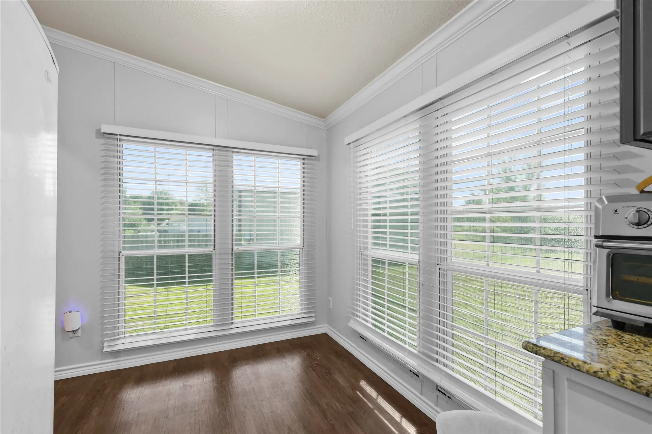 Wood-finish flooring, multiple pane windows with blinds, and white wall paneling