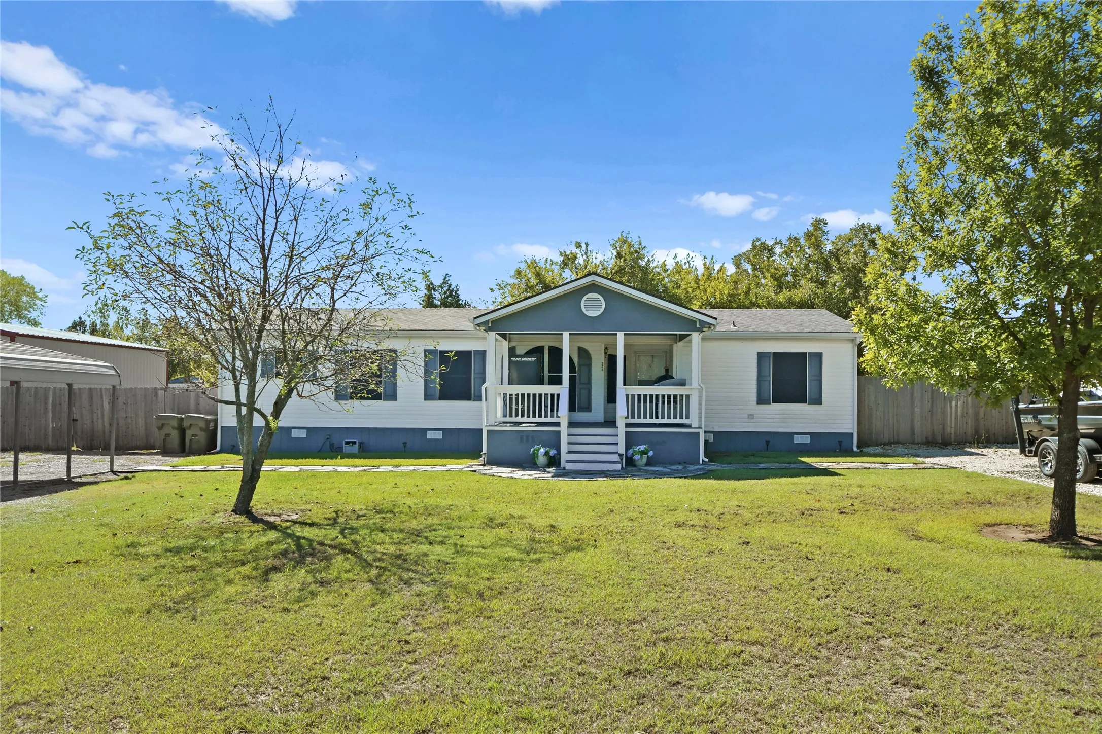 White siding exterior with a covered front porch, white porch railings, and a gravel driveway