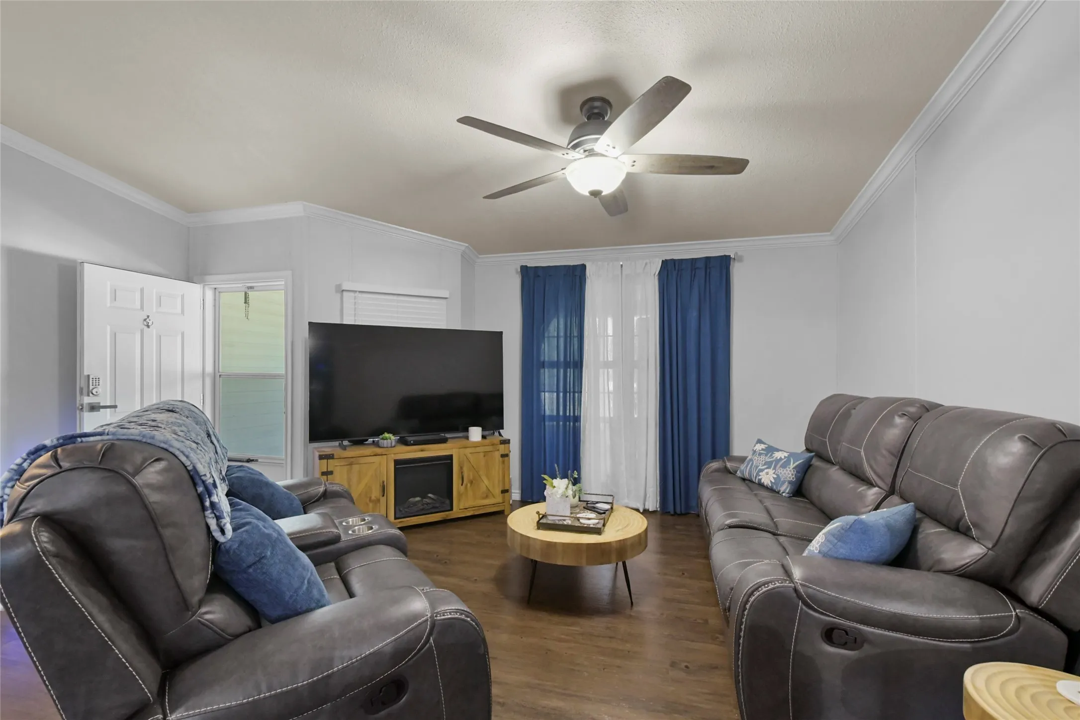 Wood-finish flooring, crown molding, and a ceiling fan with integrated lighting