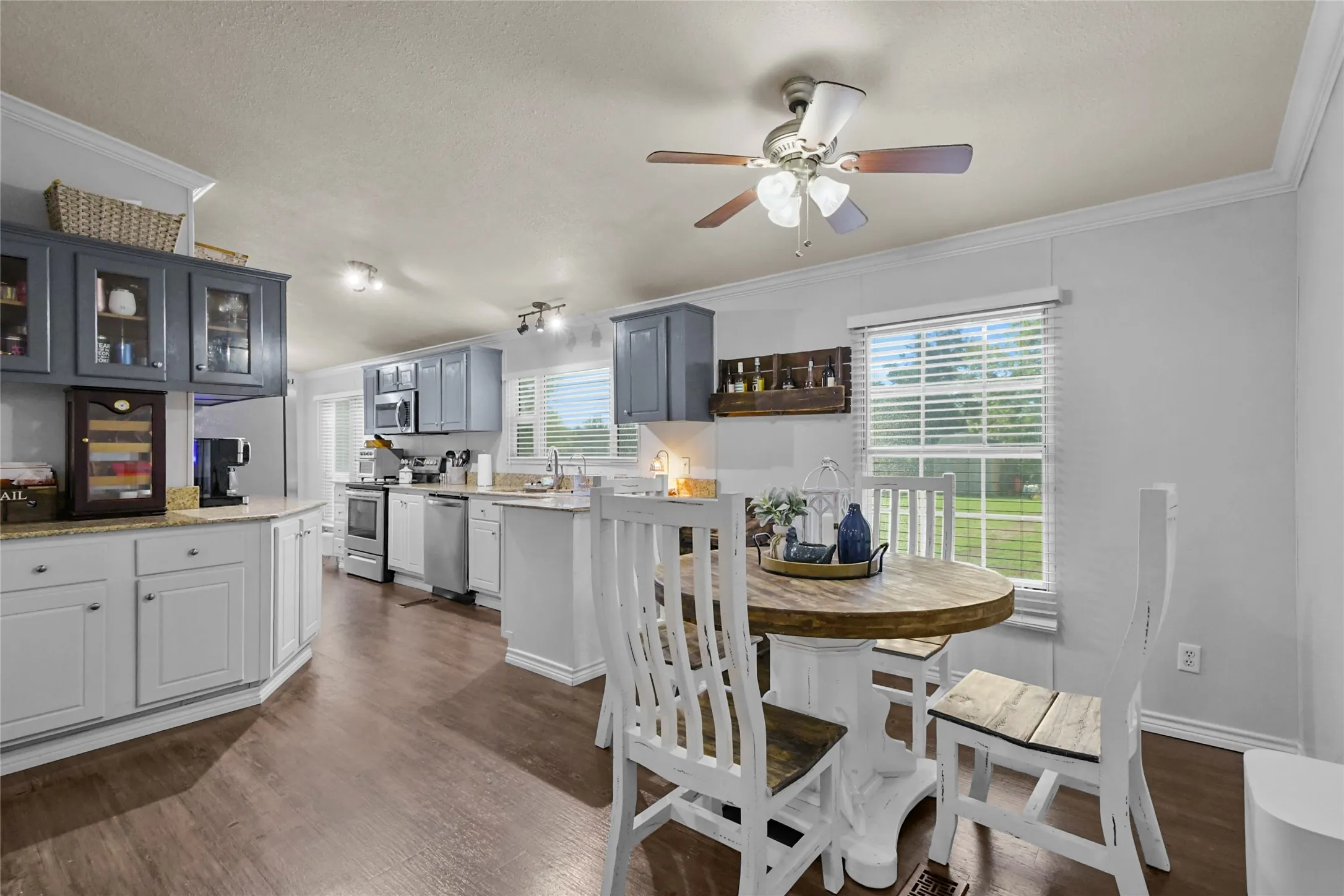 Spacious kitchen featuring wood-finish flooring, two-tone cabinetry, stainless steel appliances, and granite countertops