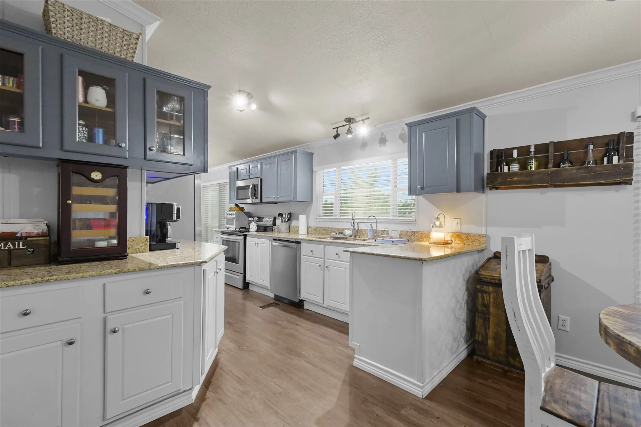 Kitchen featuring wood-finish flooring, light-toned countertops, painted cabinetry, and stainless steel appliances