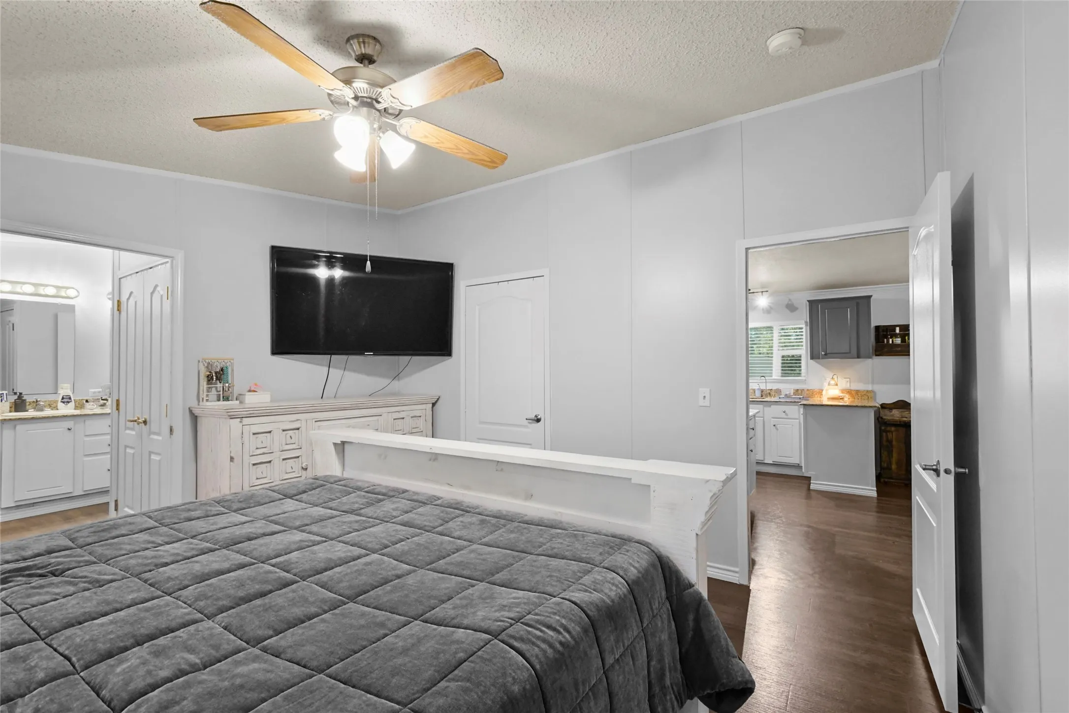 Wood-finish flooring, ceiling fan with light fixture, and white interior doors