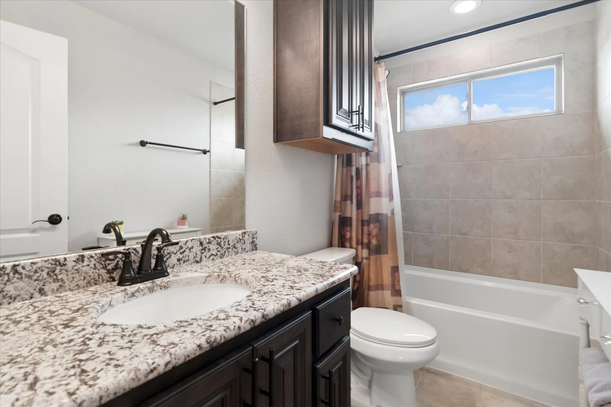 Bathroom featuring a dark wood-finish vanity with a granite countertop, undermount sink, and dark bronze fixtures