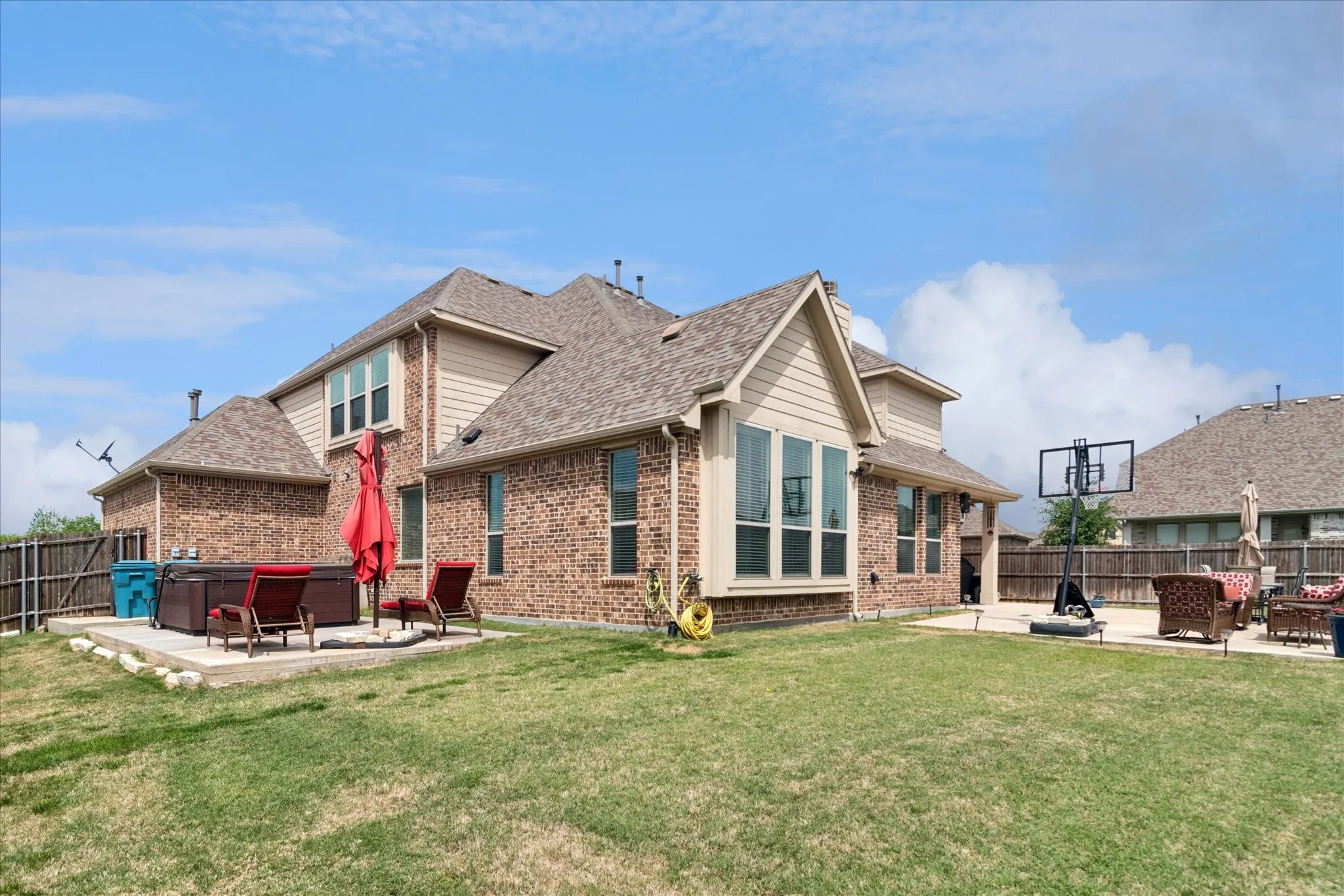 Expansive backyard featuring a manicured lawn, brick exterior, and a dedicated patio space