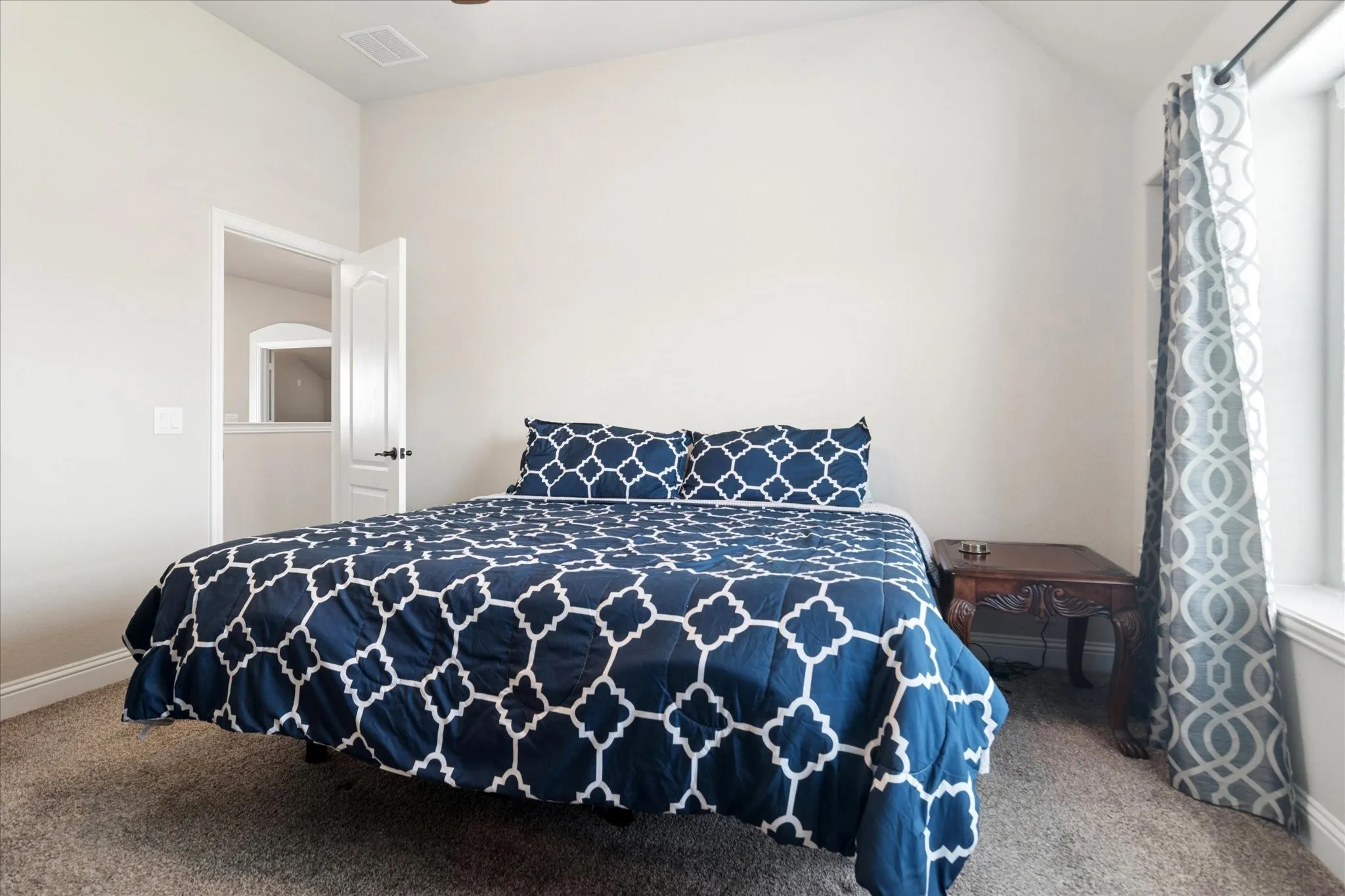 Carpeted room featuring a white interior door, light-colored walls, and a window with trim