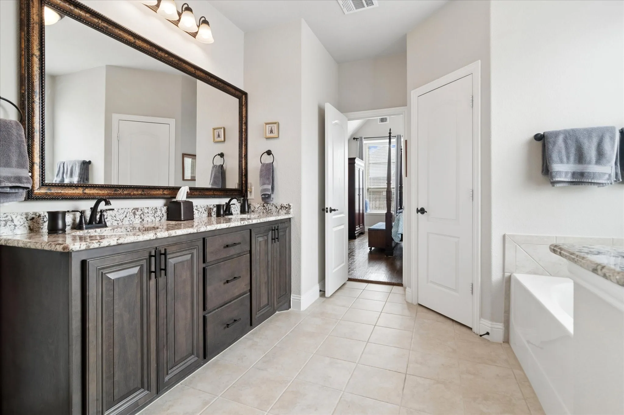 Double vanity with granite countertop, dark wood-finish cabinetry, and matte black fixtures