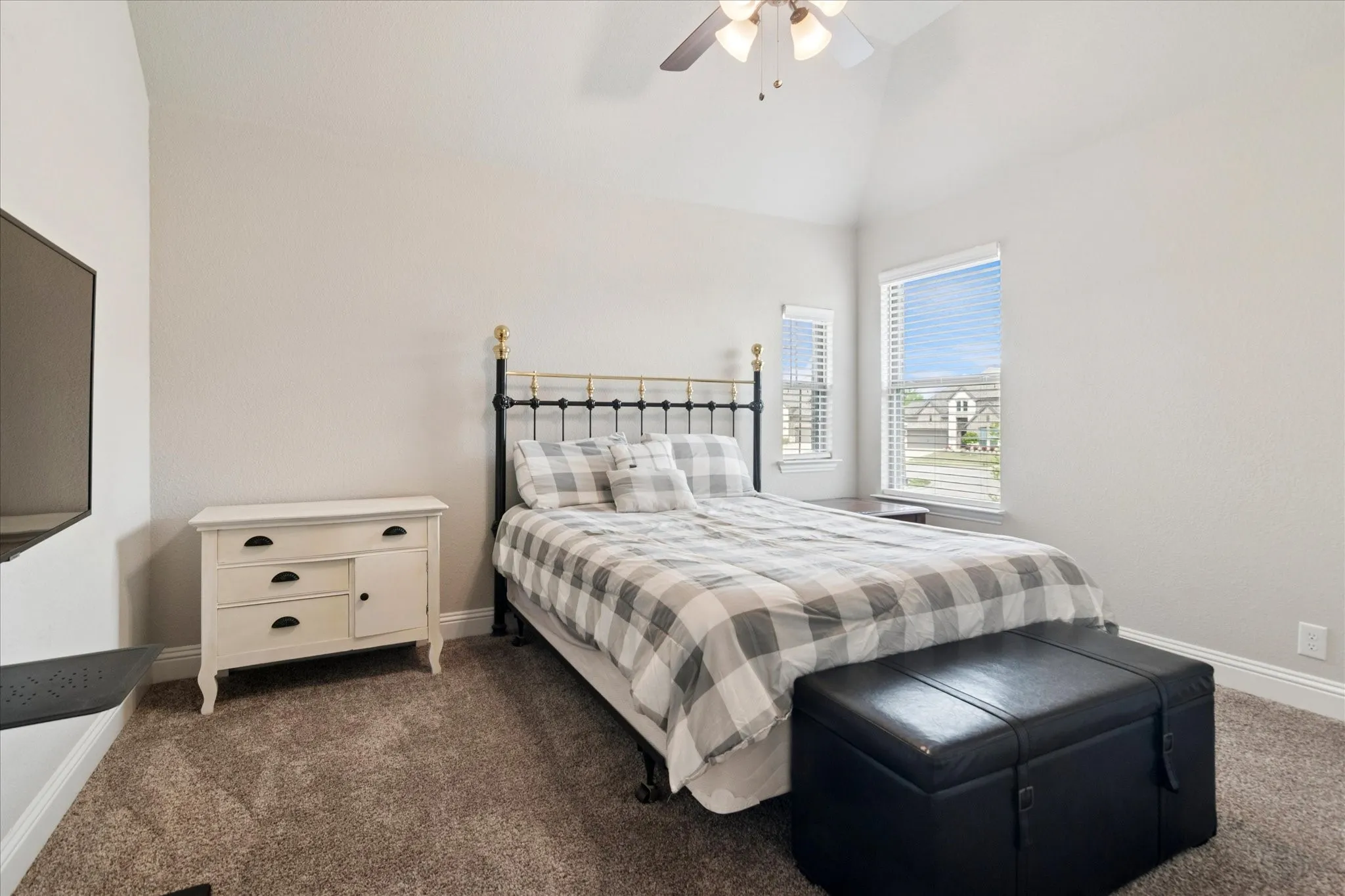 Vaulted ceiling, carpet flooring, ceiling fan, and two windows with blinds
