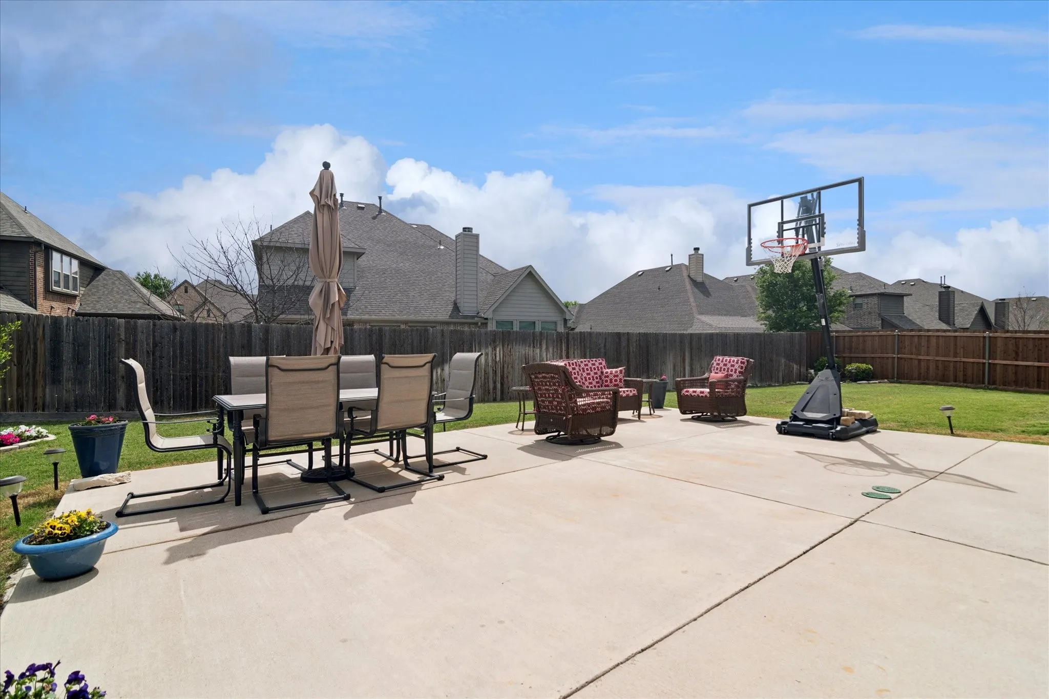 Expansive concrete patio with a surrounding wood fence and manicured lawn