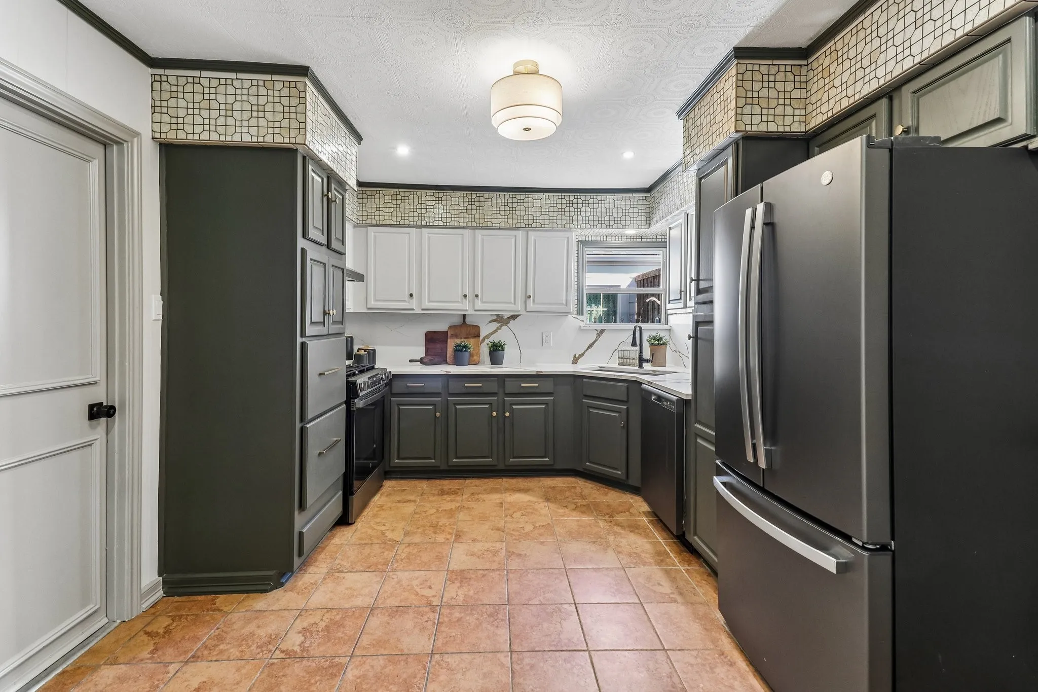 Kitchen featuring two-tone cabinetry, a patterned ceiling, and a stainless steel refrigerator