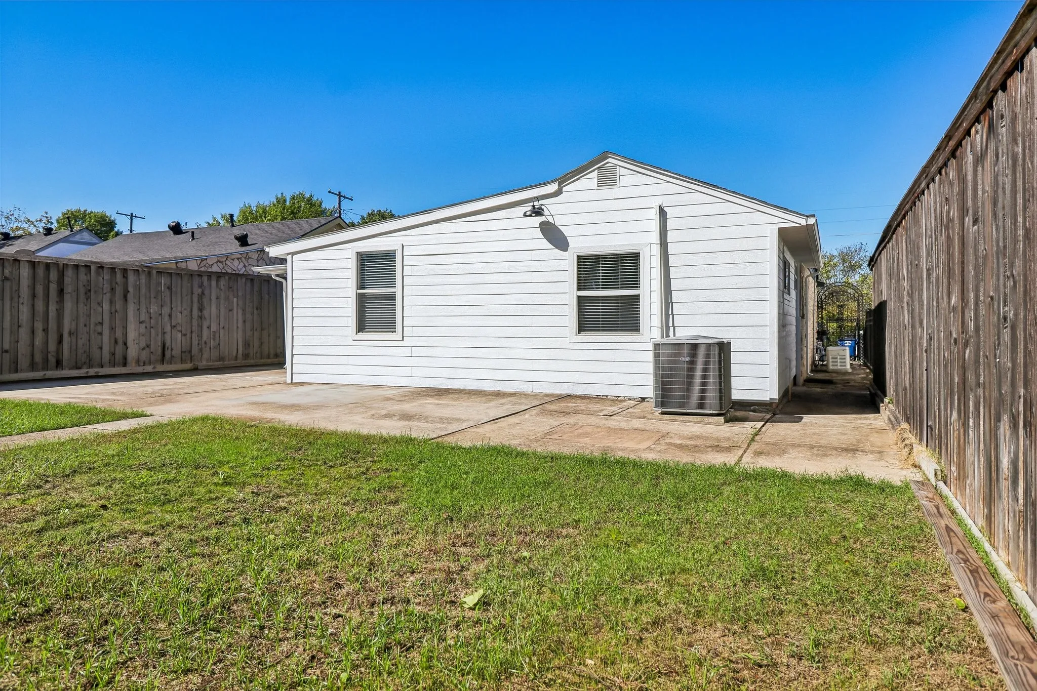 Expansive backyard featuring a manicured lawn, concrete patio, and privacy fencing