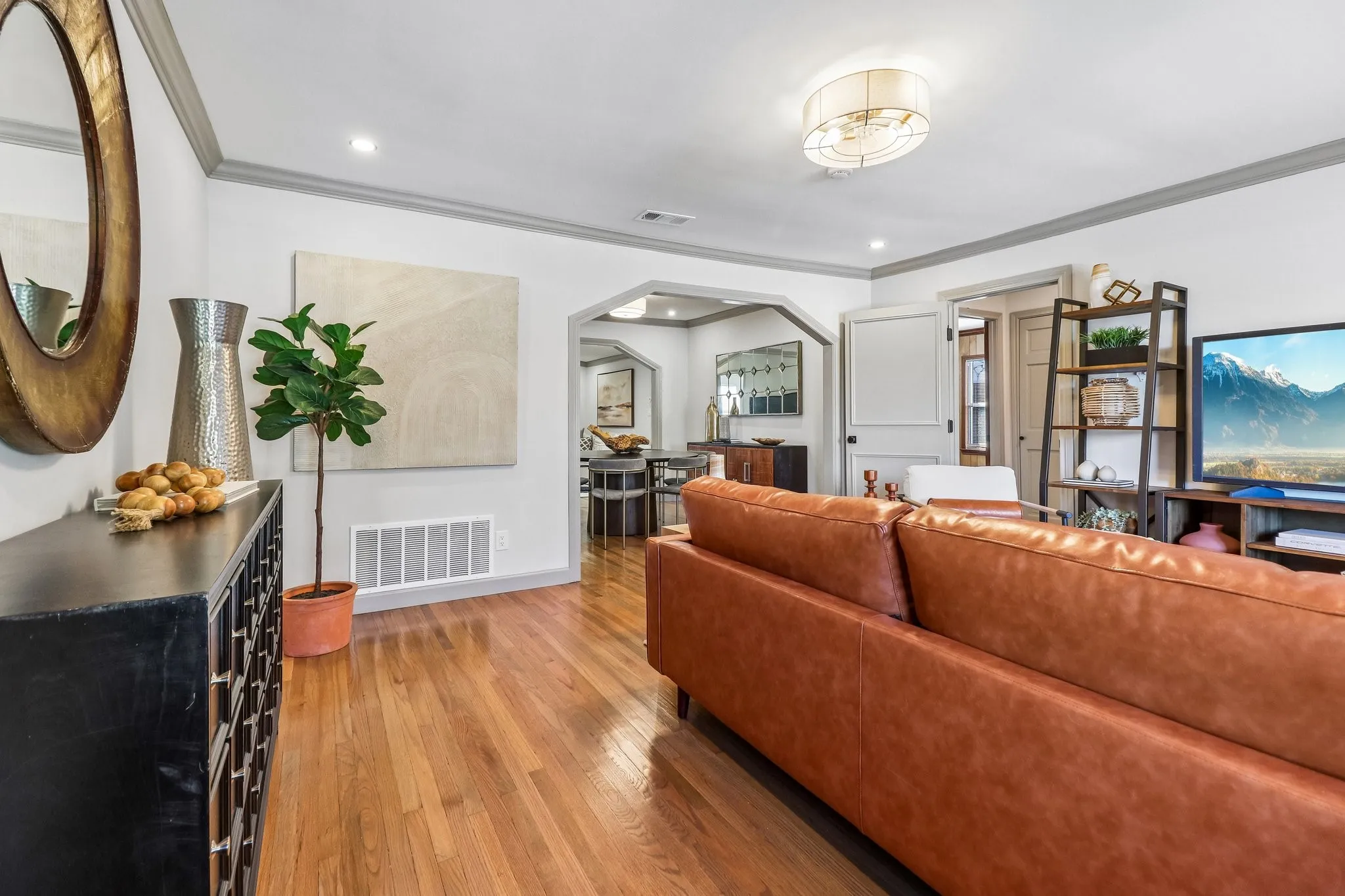 Hardwood flooring, recessed lighting, archway entry, crown molding, and a drum ceiling light fixture