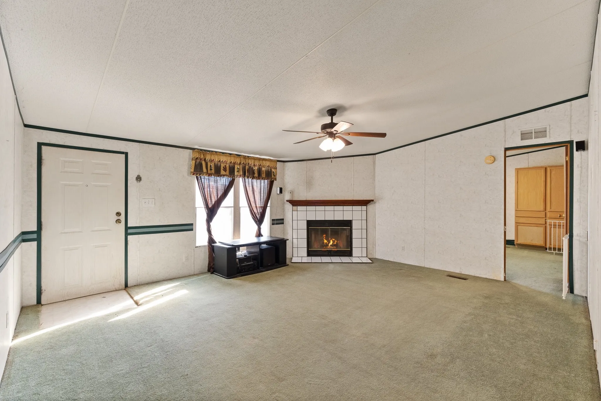 Living room with tiled fireplace and mantle along with windows for natural lighting and ceiling fan.