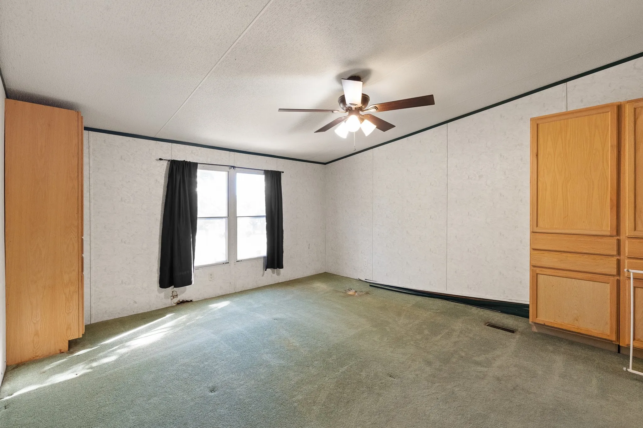 Master bedroom with cabinetry for storage, ceiling fan and windows for natural lighting.