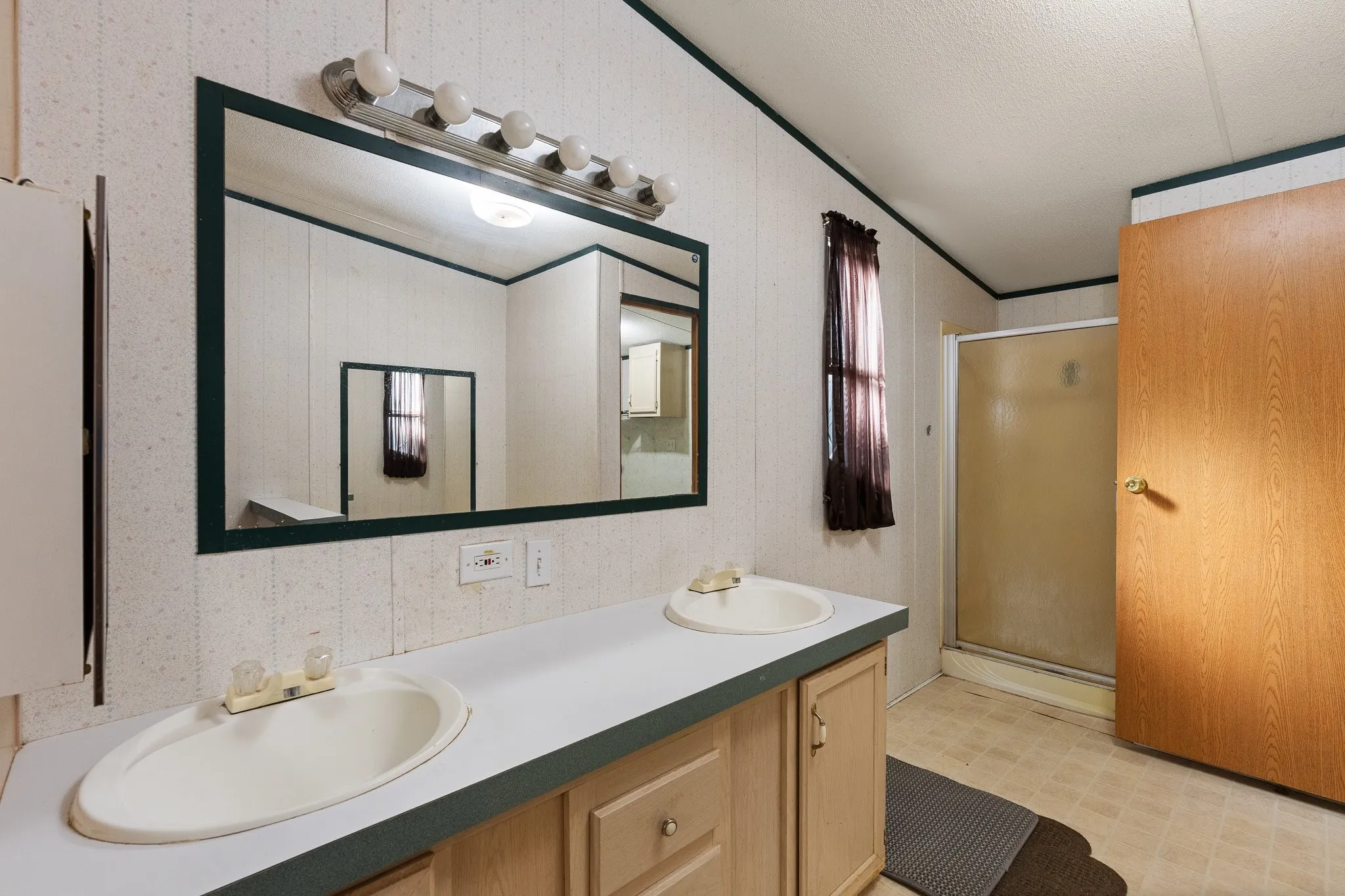 Master bathroom with Dual sink vanity w/ mirror and lighting along with lighter colored cabinetry.