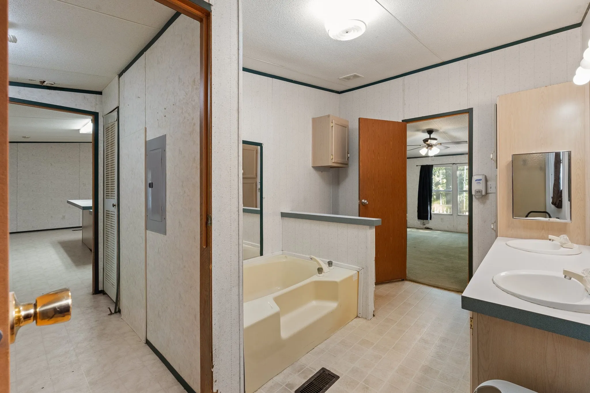 Master bathroom with dual sink vanity, garden tub, and lighter colored cabinetry for storage.