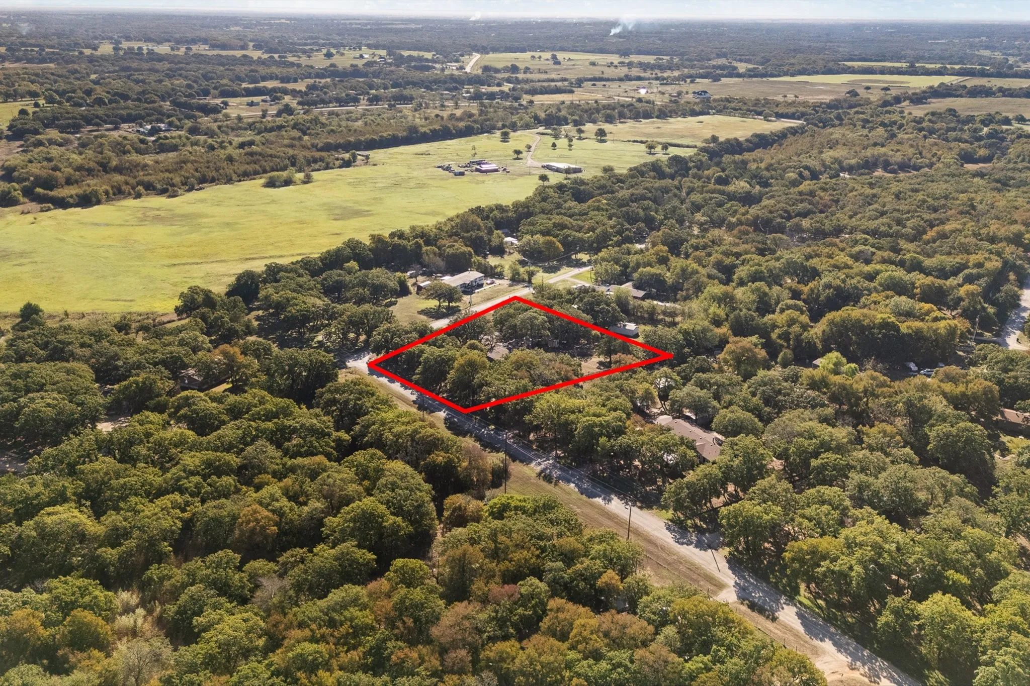 Aerial view of home surrounded by trees and farmland.