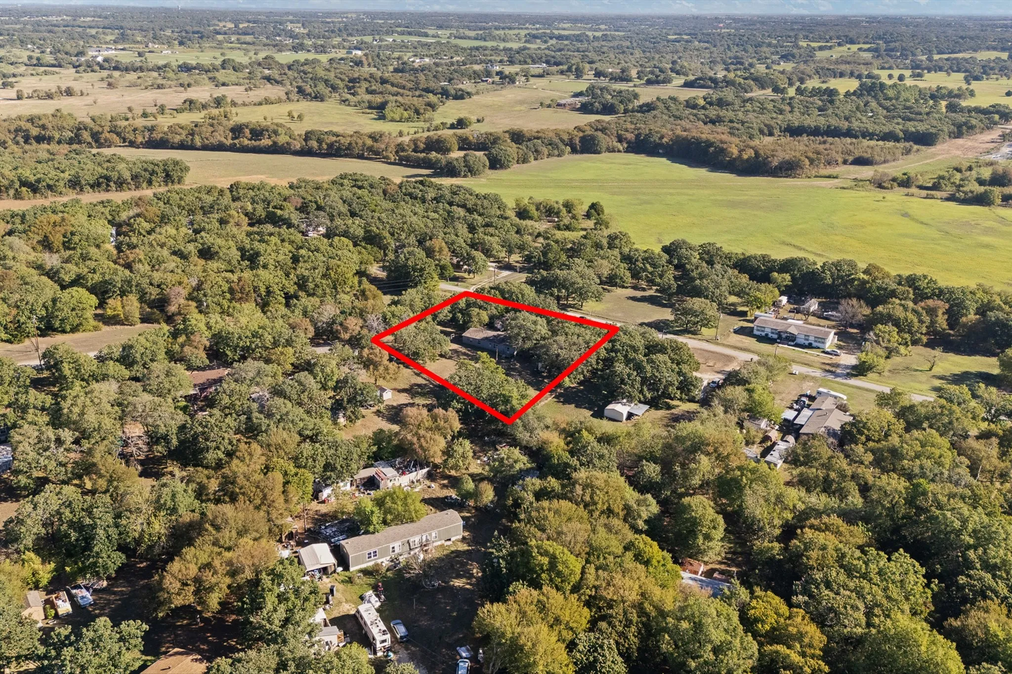 Aerial View of home surrounded by lots of mature trees for privacy and farmland.