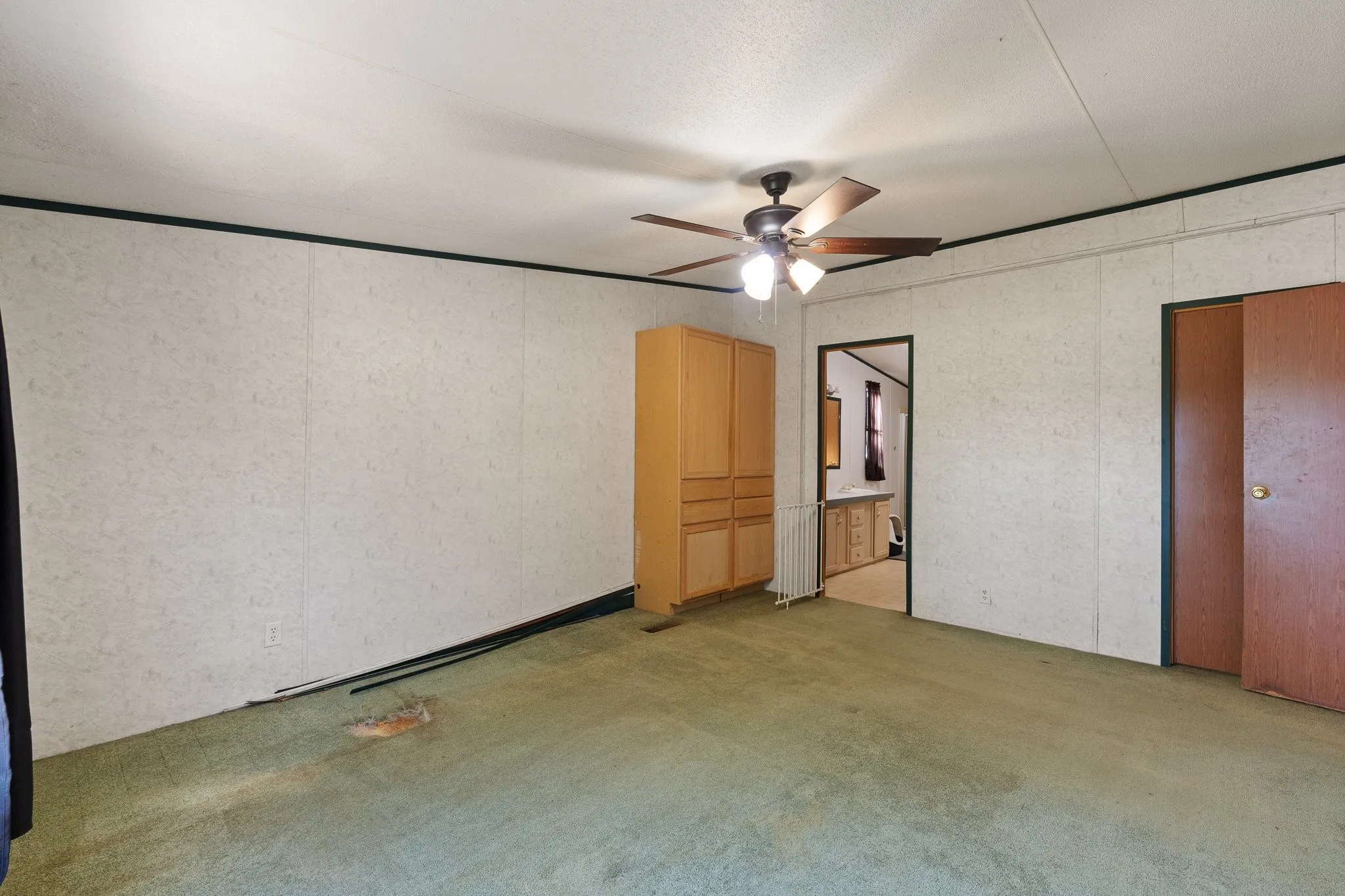 Master bedroom with ceiling fan, walk in closet, and cabinetry for storage.