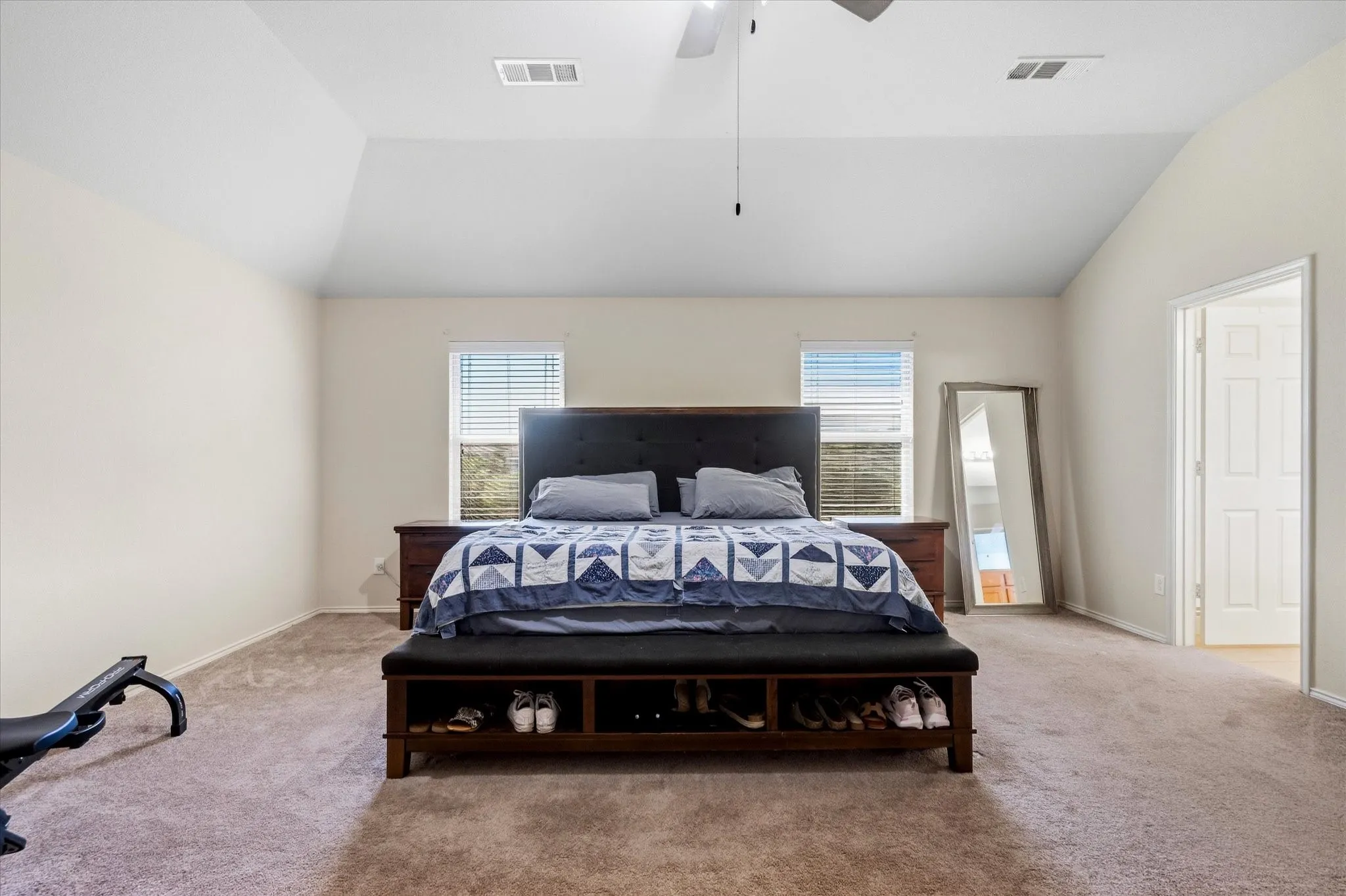 Vaulted ceilings, neutral wall paint, carpet flooring, ceiling fan, and multiple windows with blinds