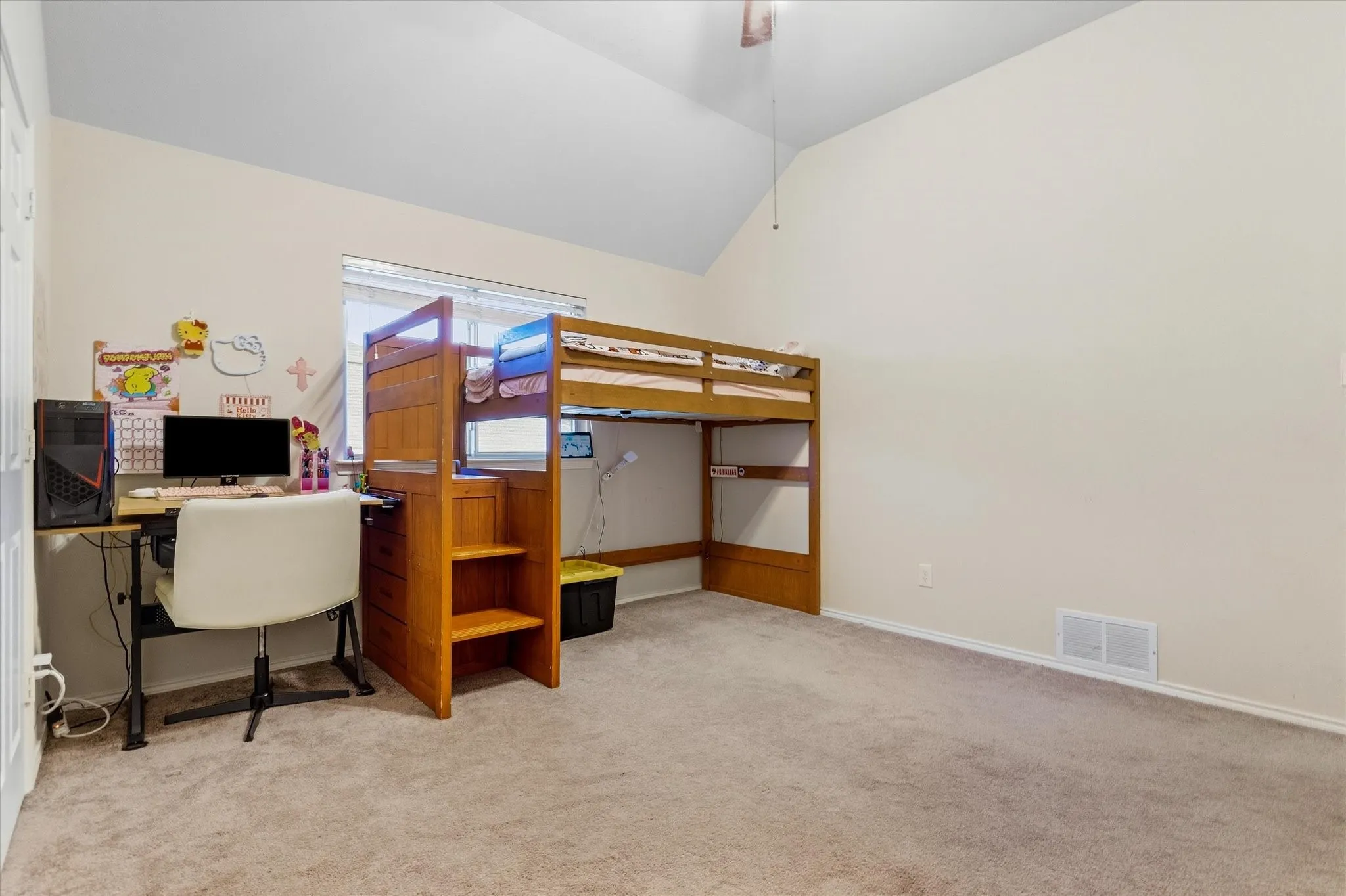 Vaulted ceiling, ceiling fan, carpet flooring, window with blinds, wood-finish built-in shelving unit