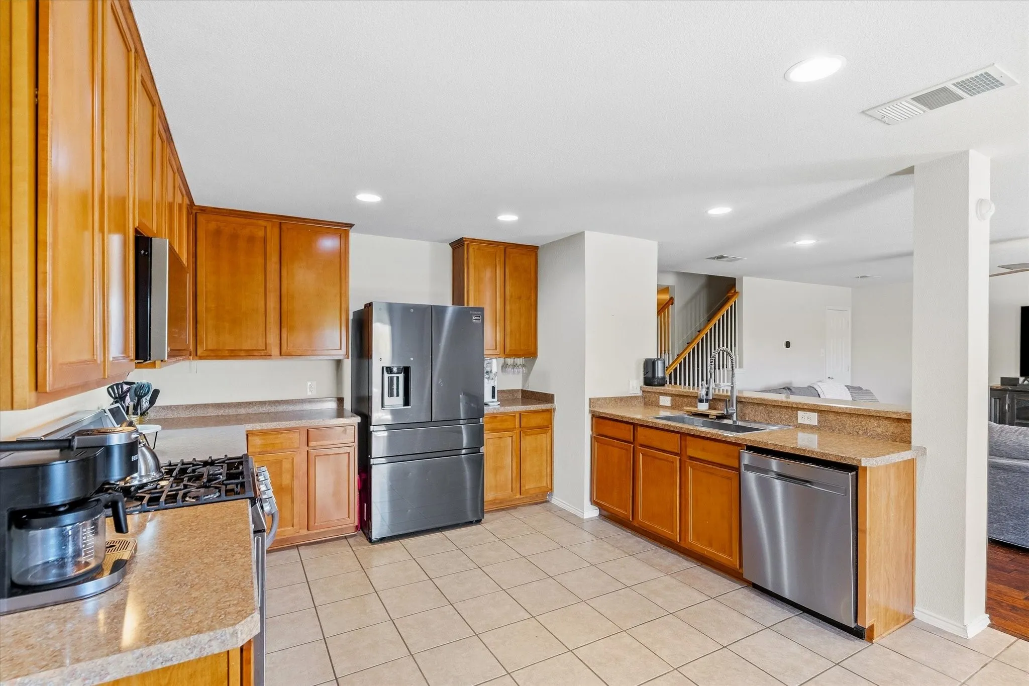 Kitchen featuring wood cabinetry, stone-finish countertops, stainless steel appliances, and tile flooring