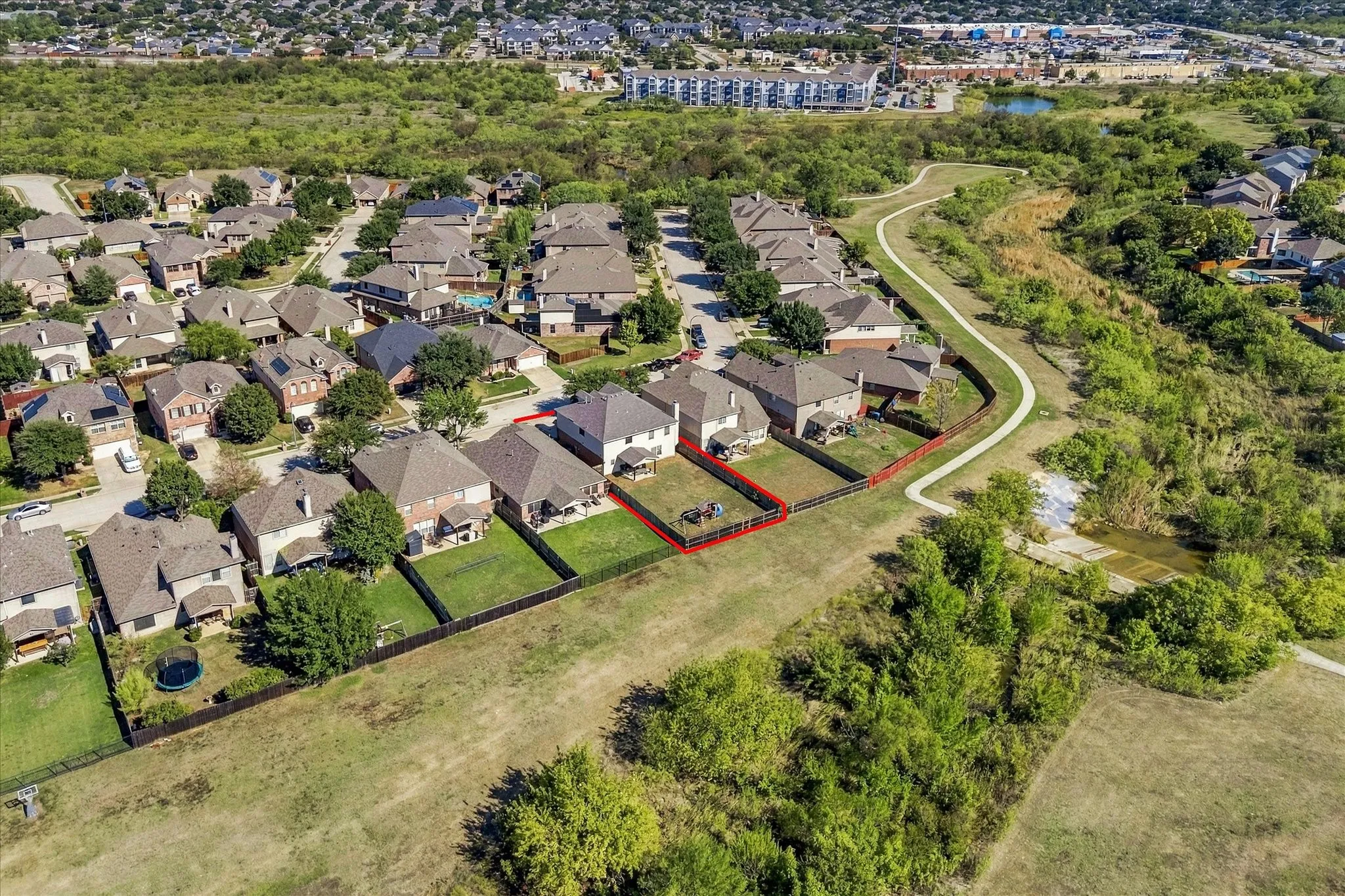 Residential properties with fenced backyards situated alongside a paved walking path