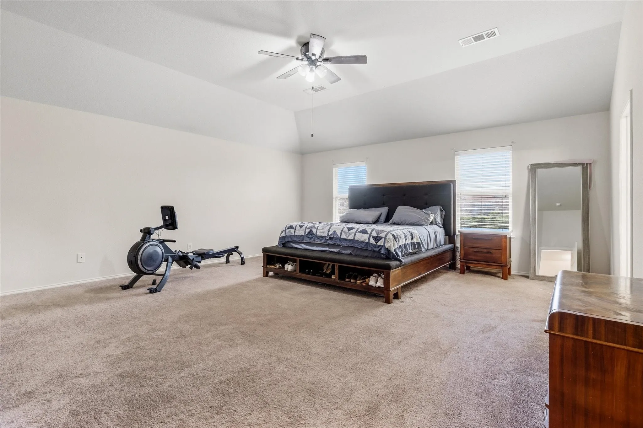 Spacious room featuring vaulted ceilings, light-colored walls, and neutral carpet flooring