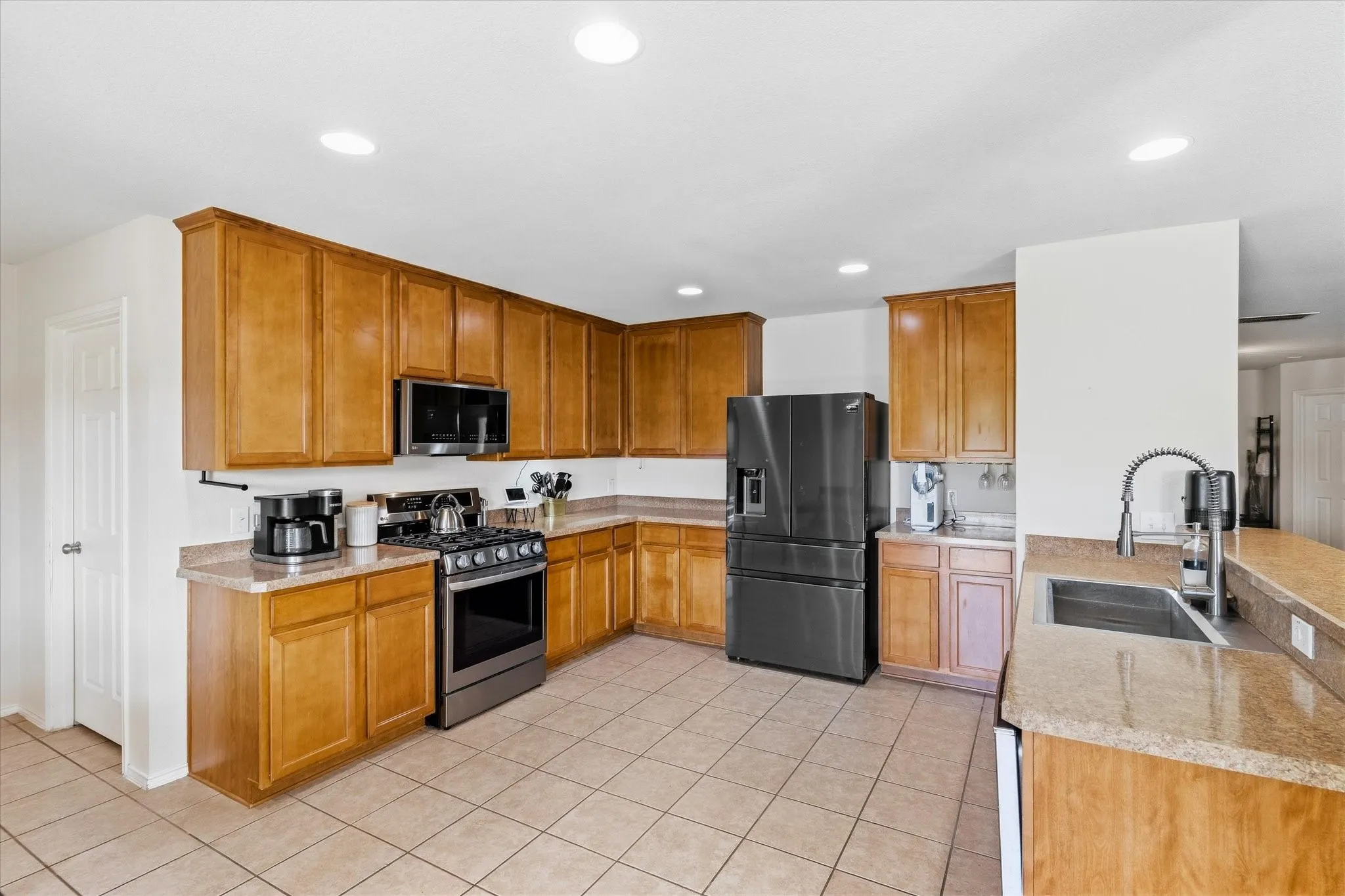 Kitchen featuring extensive wood cabinetry, L-shaped countertop, stainless steel appliances, a kitchen island, and recessed lighting
