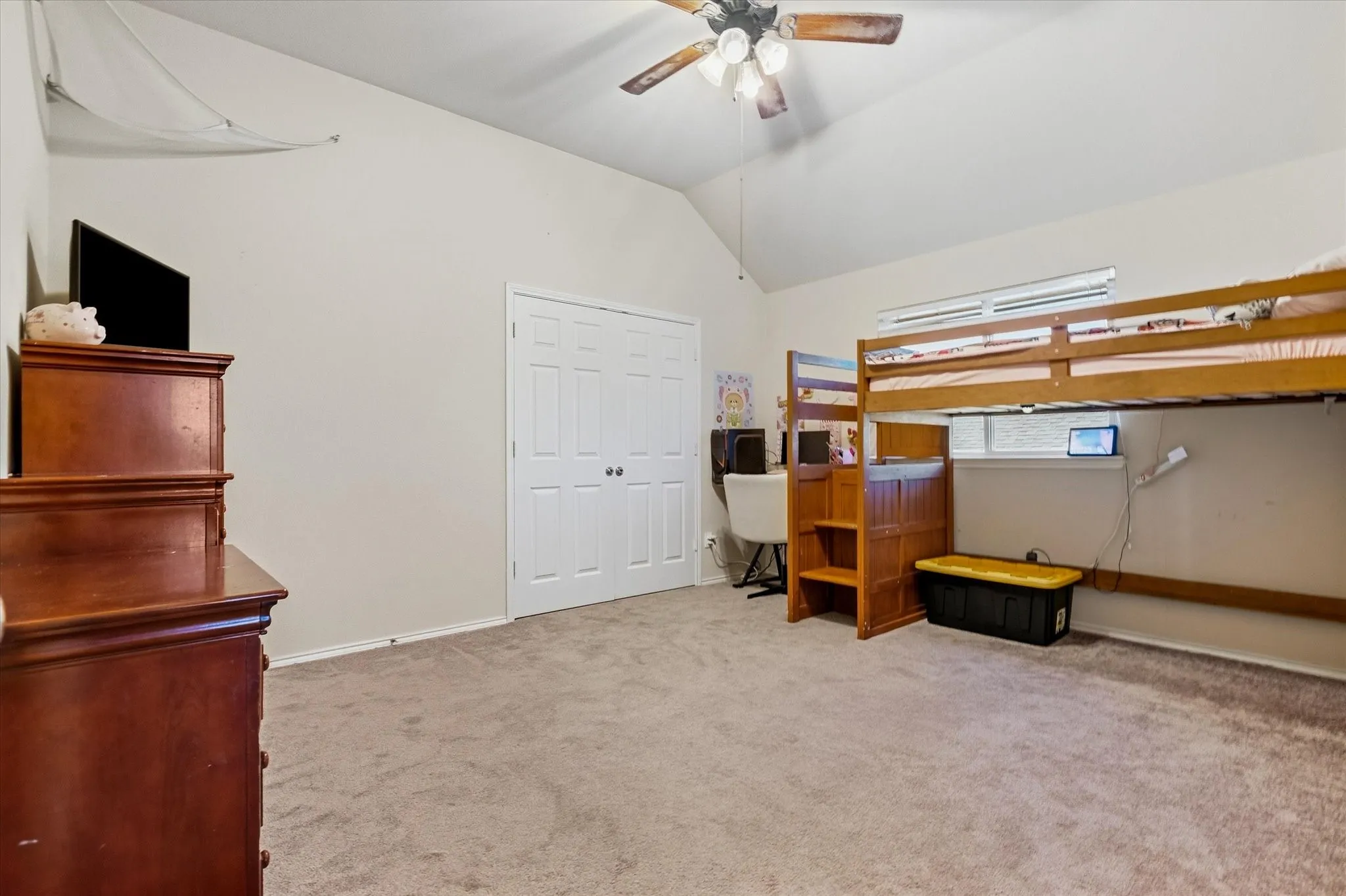 Vaulted ceiling with a ceiling fan, light-toned carpet, and a window with blinds