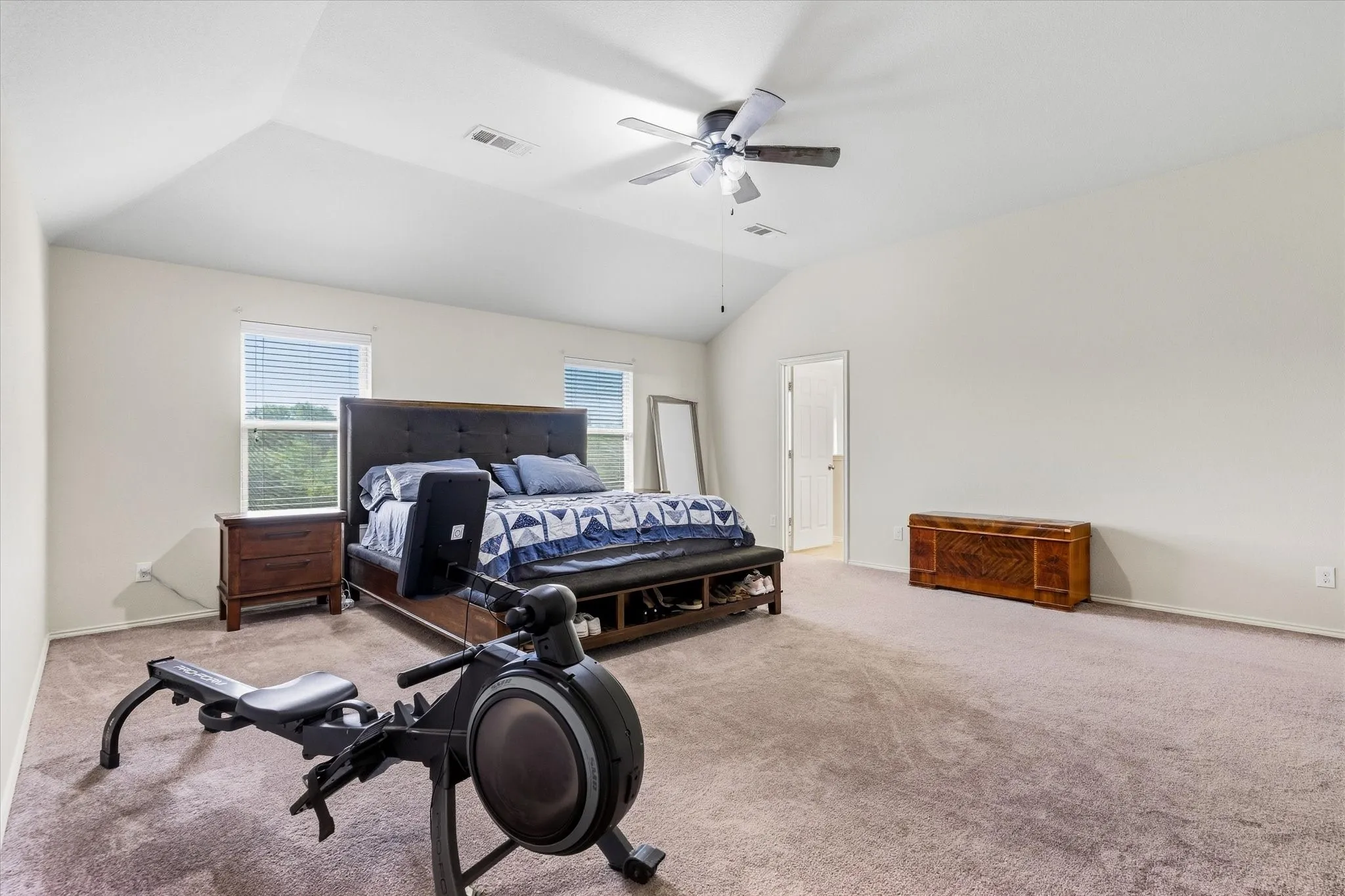 Vaulted ceiling with a ceiling fan, dual windows with blinds, and neutral carpet flooring