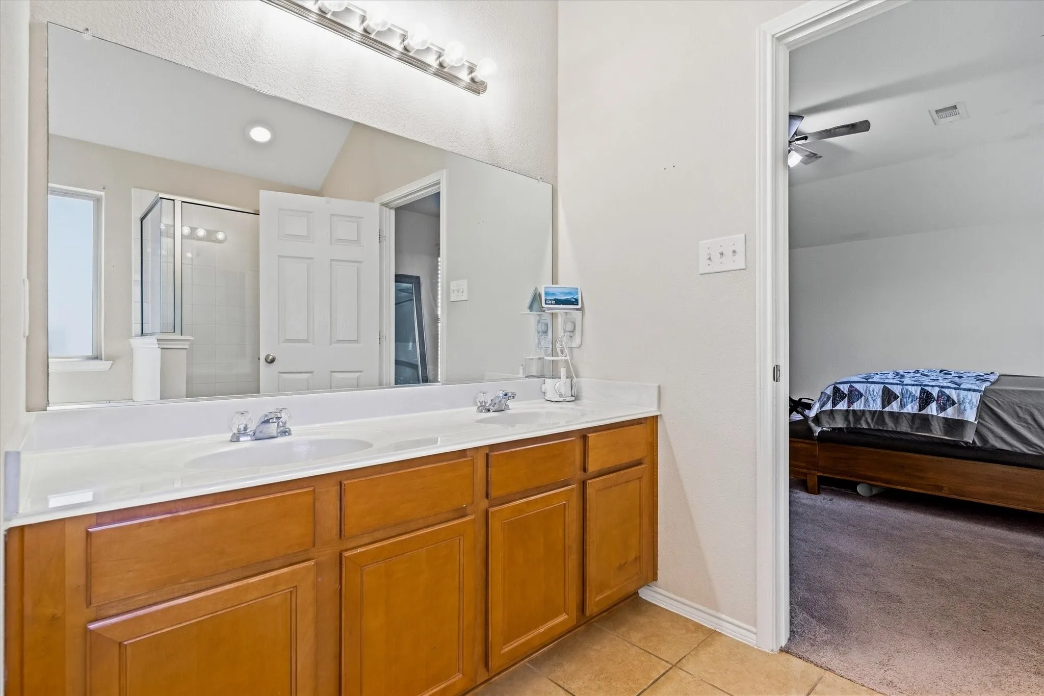 Double vanity with integrated sinks, wood-finish cabinetry, and a full-width mirror