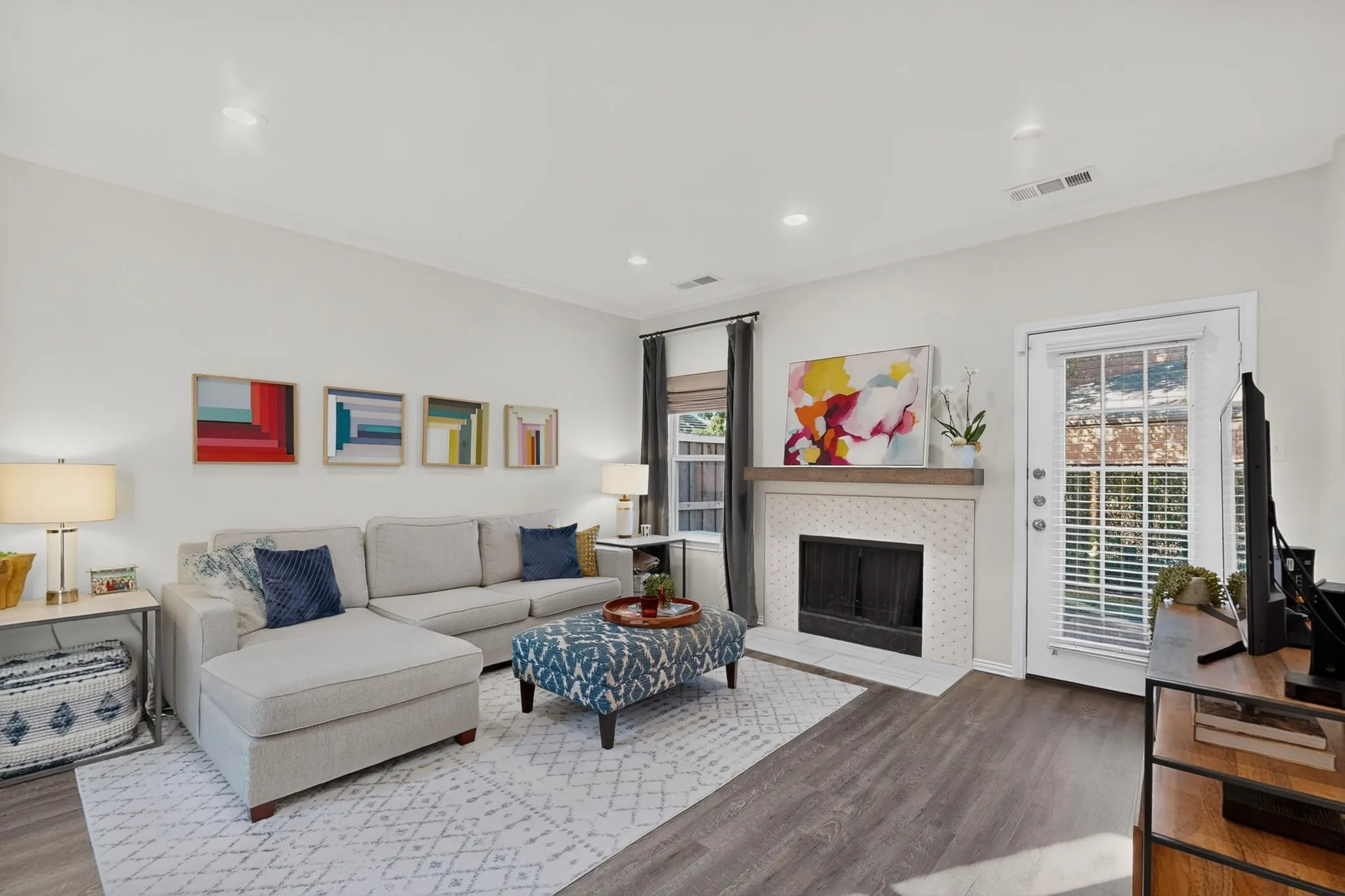 Living space with wood-finish flooring, a white tiled fireplace, and a light wood mantel