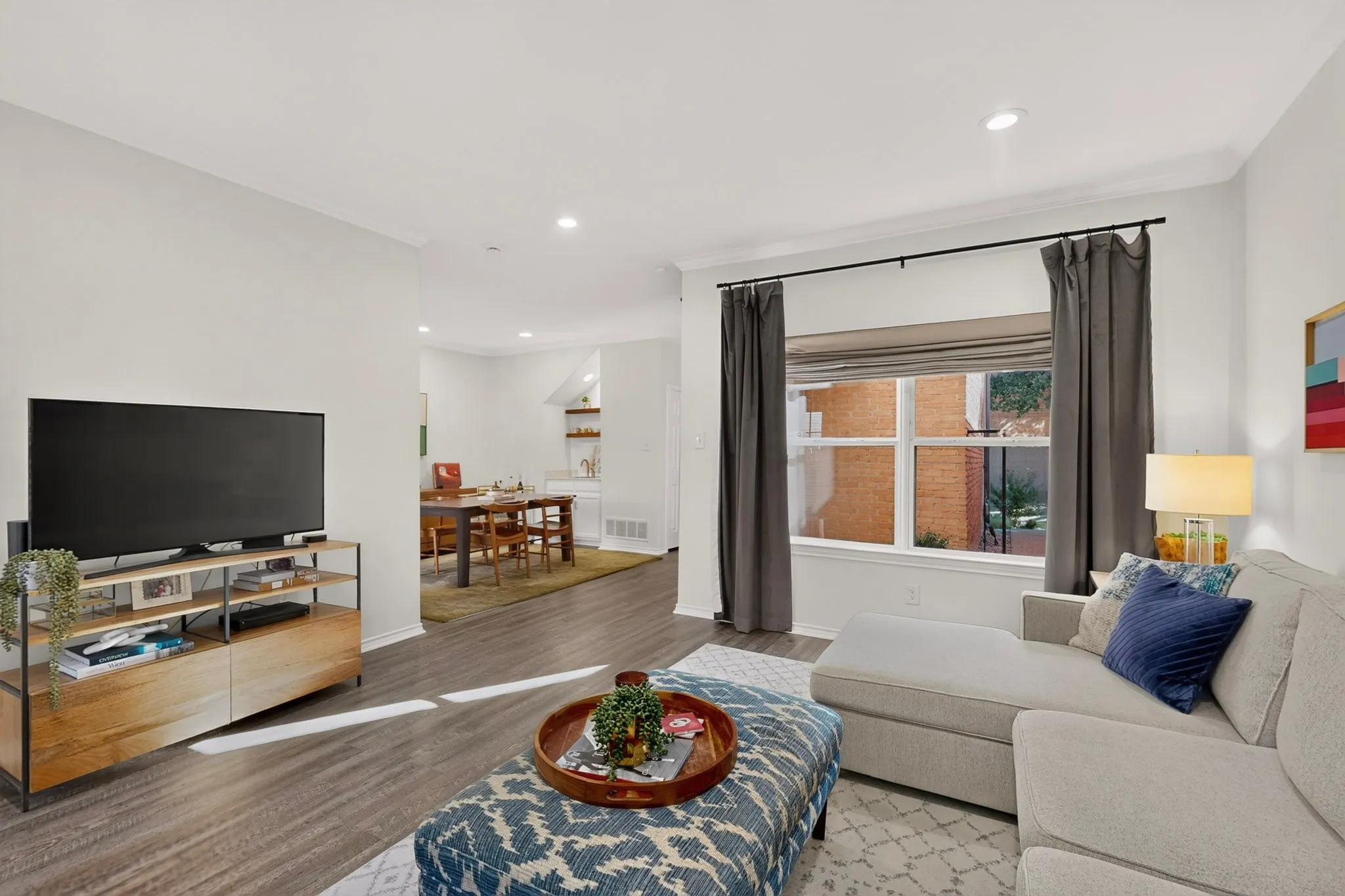 Recessed lighting, crown molding, wood-finish flooring, and a large window with white trim