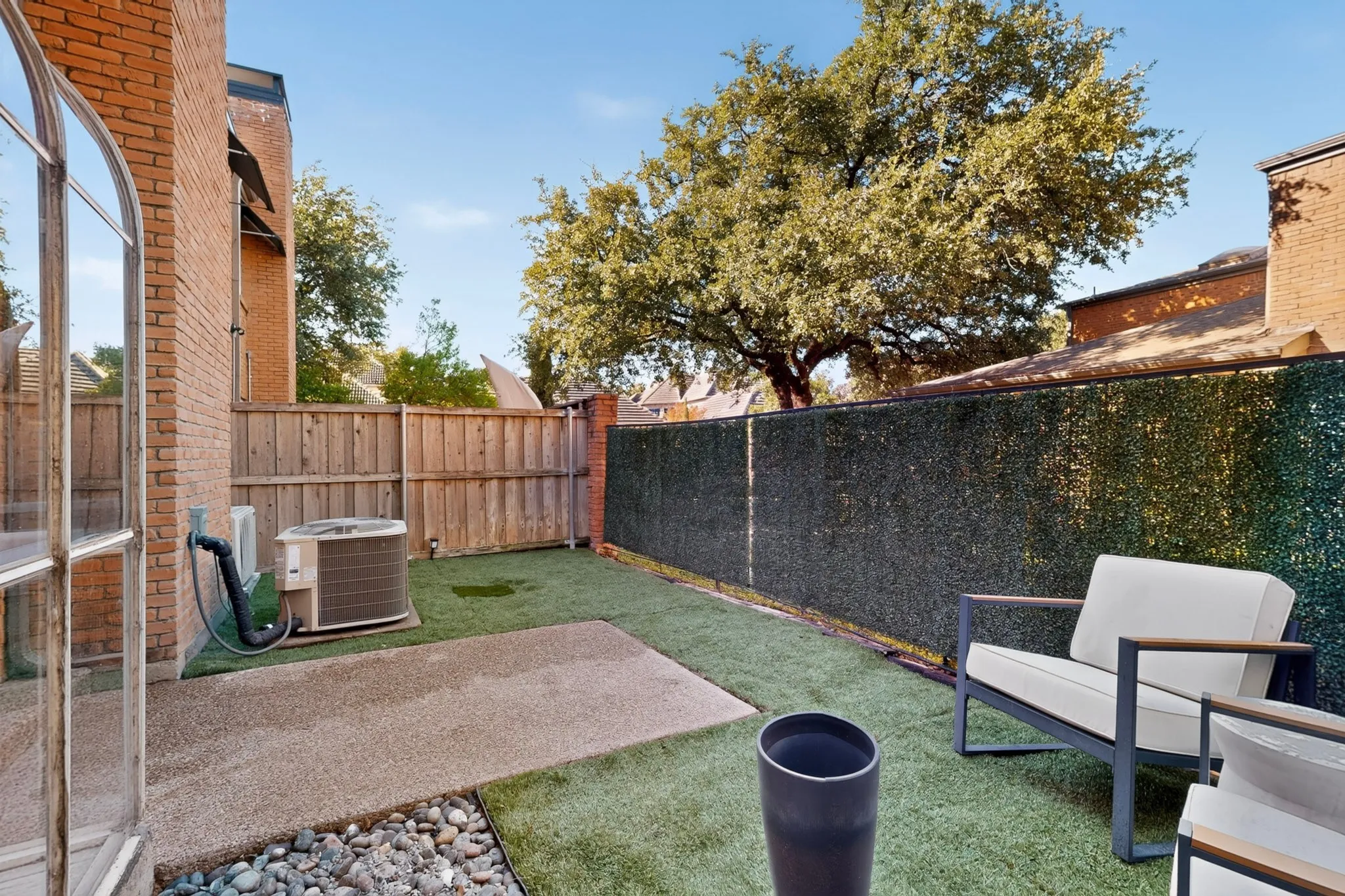 Private exterior space featuring artificial turf, a paved patio, and a stone-lined border