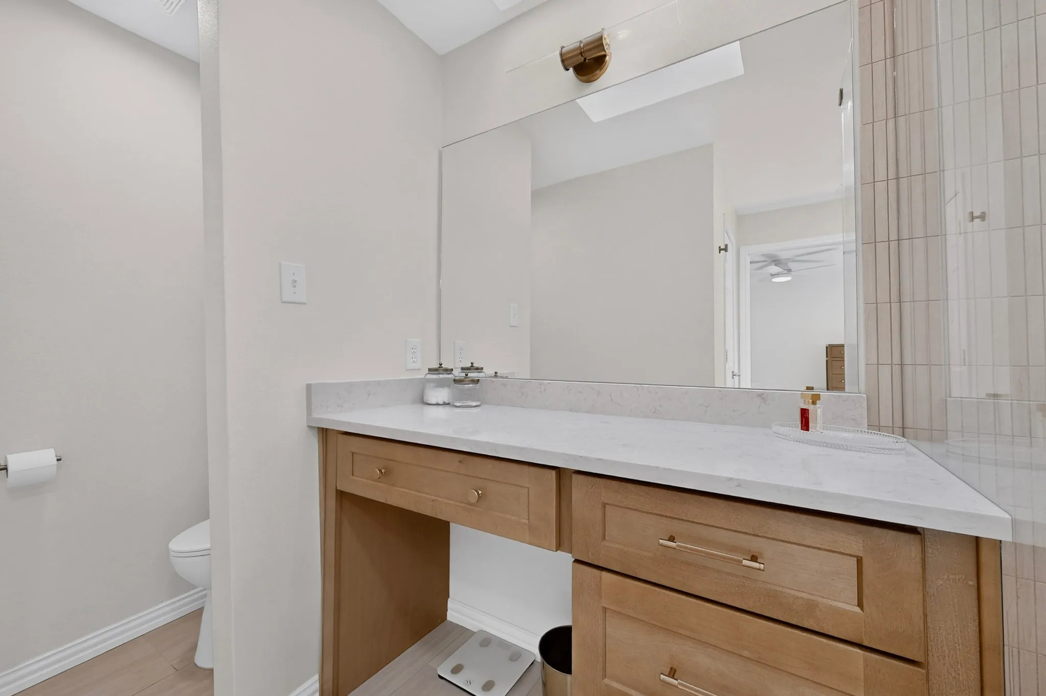 Vanity with light wood-finish cabinetry, white countertop, and integrated mirror