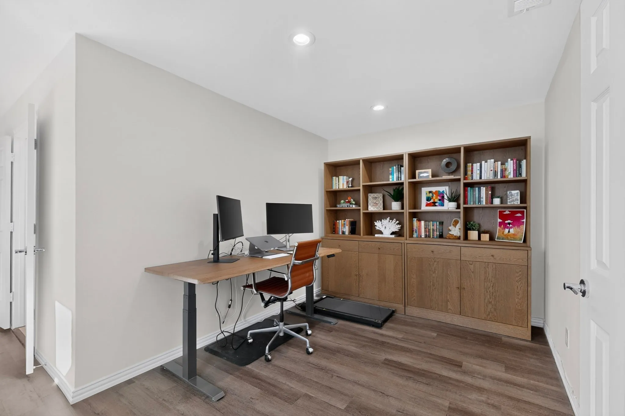 Wood-finish flooring, recessed lighting, built-in shelving with integrated cabinetry, and painted white trim